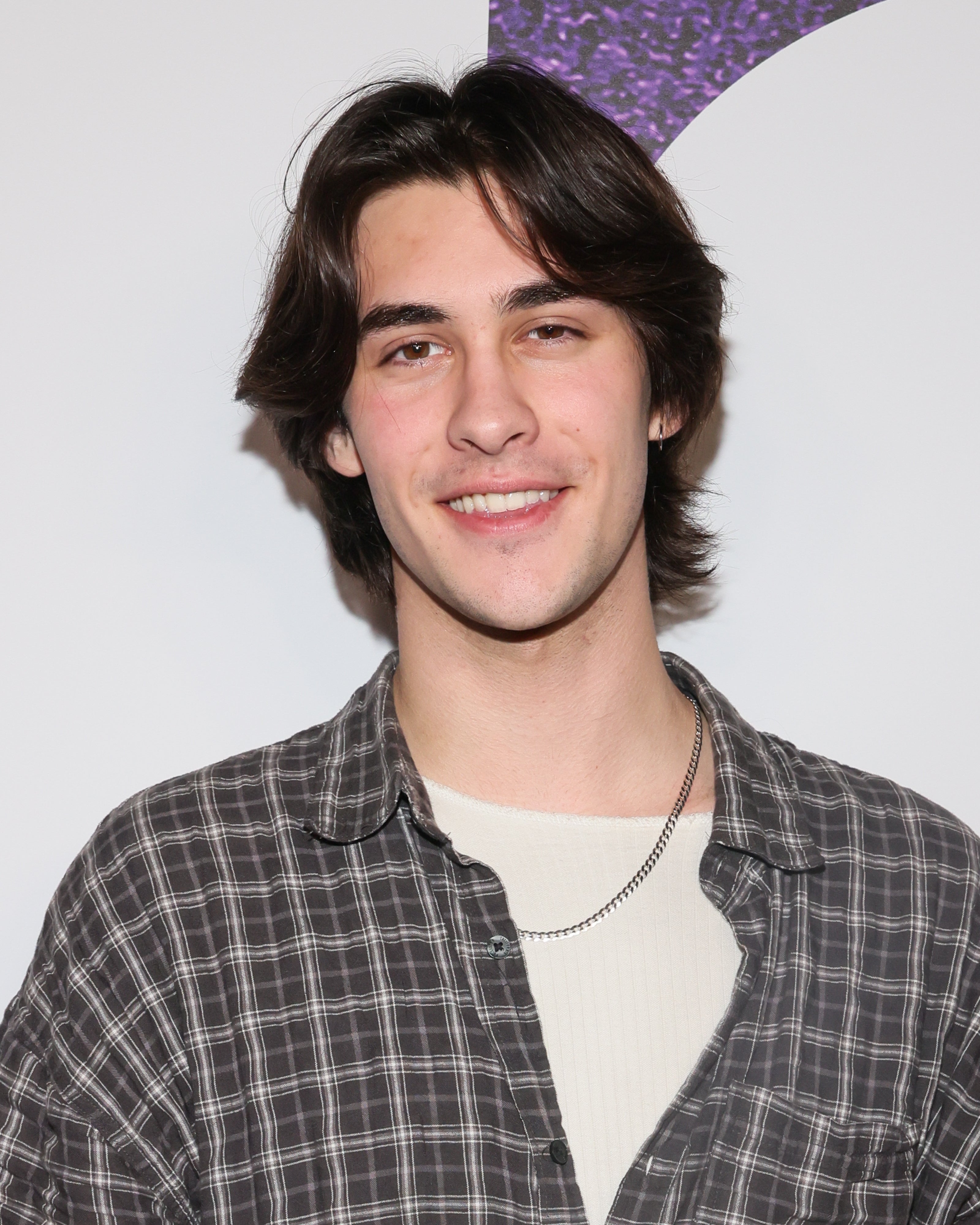 Person in a plaid shirt poses at a TV and movie industry event, smiling at the camera
