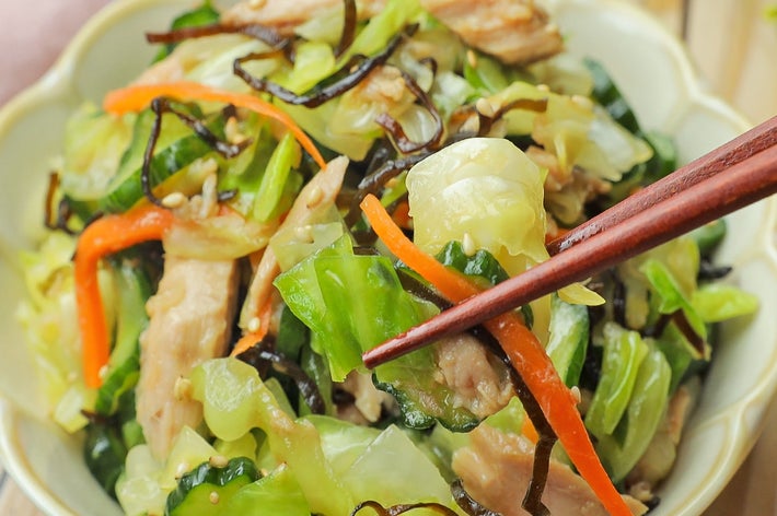 皿に盛られた野菜炒め。にんじん、キャベツ、肉、昆布が使われた料理。箸で一部を持ち上げている。