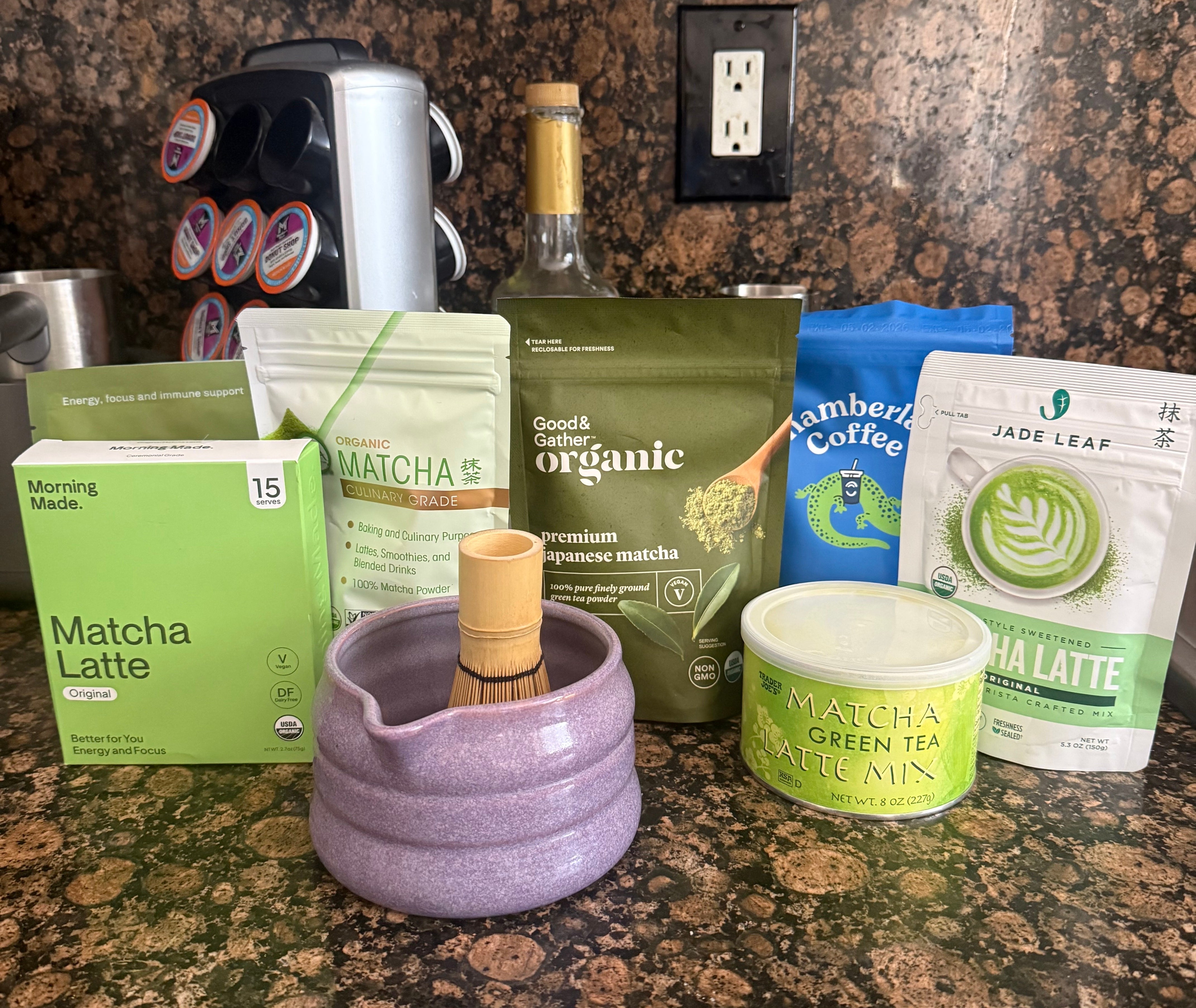 Matcha-themed kitchen counter with different matcha tea products, a whisk, and a bowl