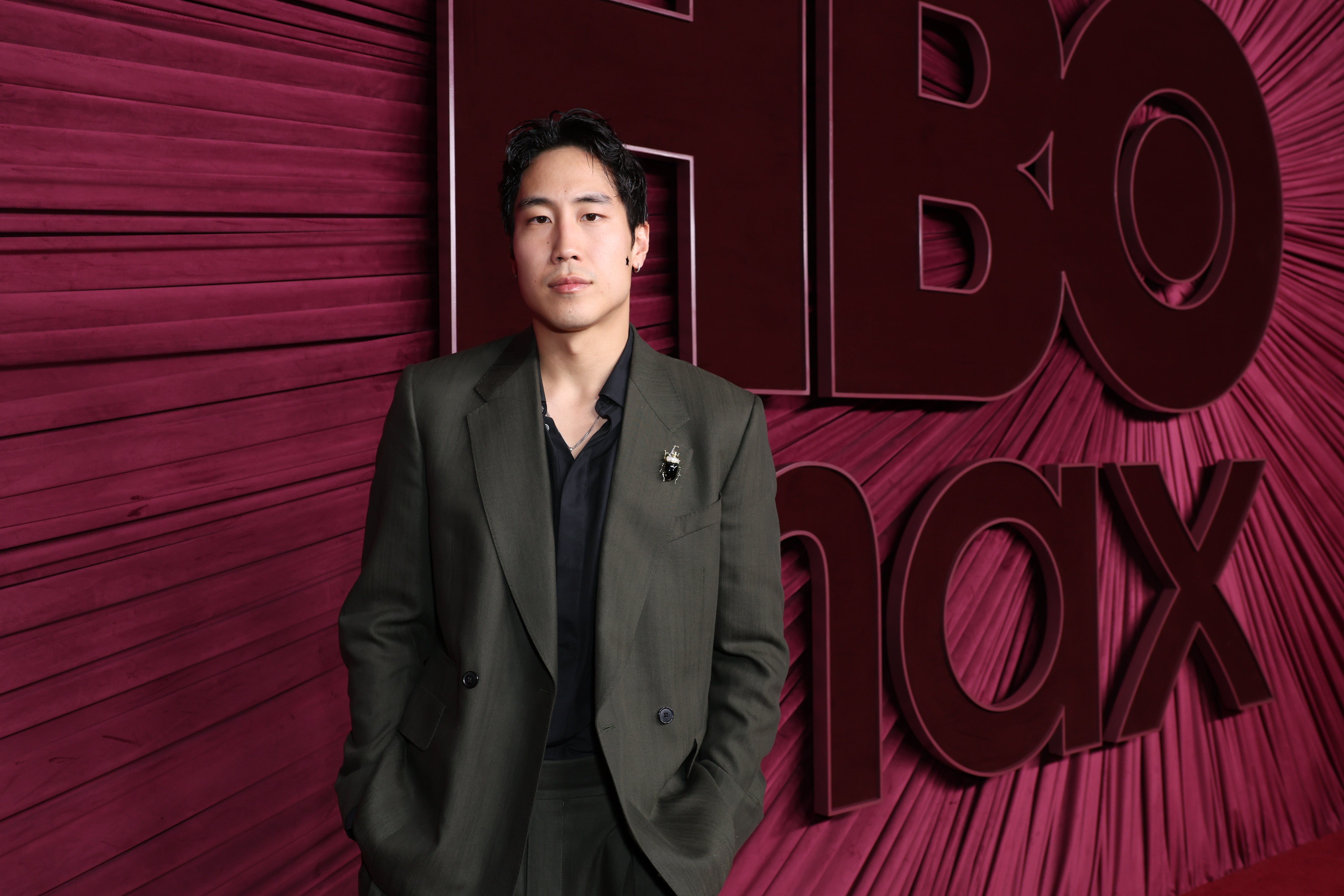 Person in a tailored suit poses in front of an HBO Max backdrop