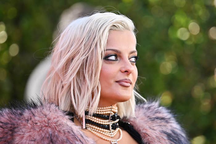 Bebe Rexha with abbreviated  hairsbreadth  wearing a fur-trimmed outfit, layered necklaces, and melodramatic  oculus  makeup, gazes to the broadside  astatine  a reddish  carpet event