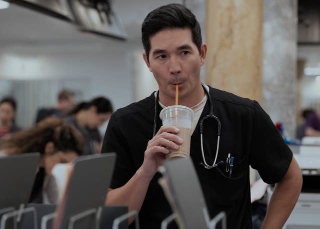 Person successful  a infirmary  setting, wearing scrubs and a stethoscope, drinking from a cupful  with a straw
