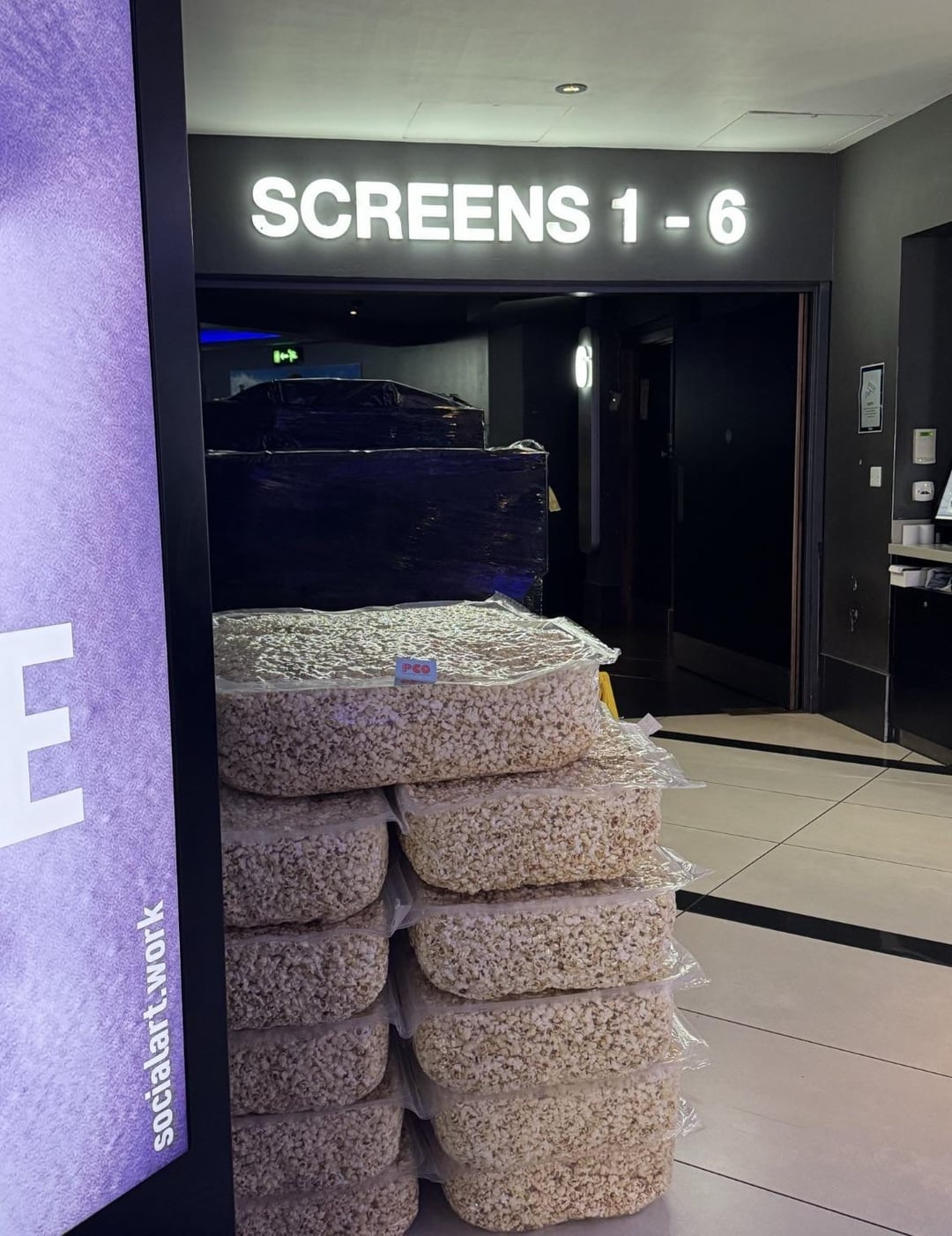 Tumpukan tas popcorn di lorong bioskop di bawah tanda baca 