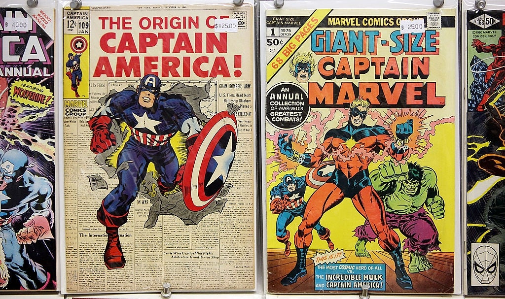 Comic publication covers of "The Origin of Captain America" and "Giant-Size Captain Marvel," featuring superheroes Captain America and Captain Marvel