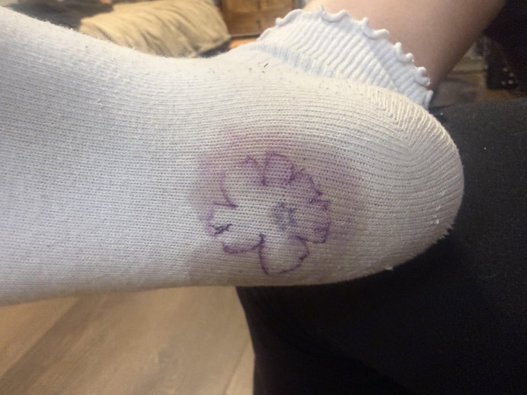 Kaus kaki dengan cetakan tinta bunga di bagian bawah, dikenakan di kaki seseorang