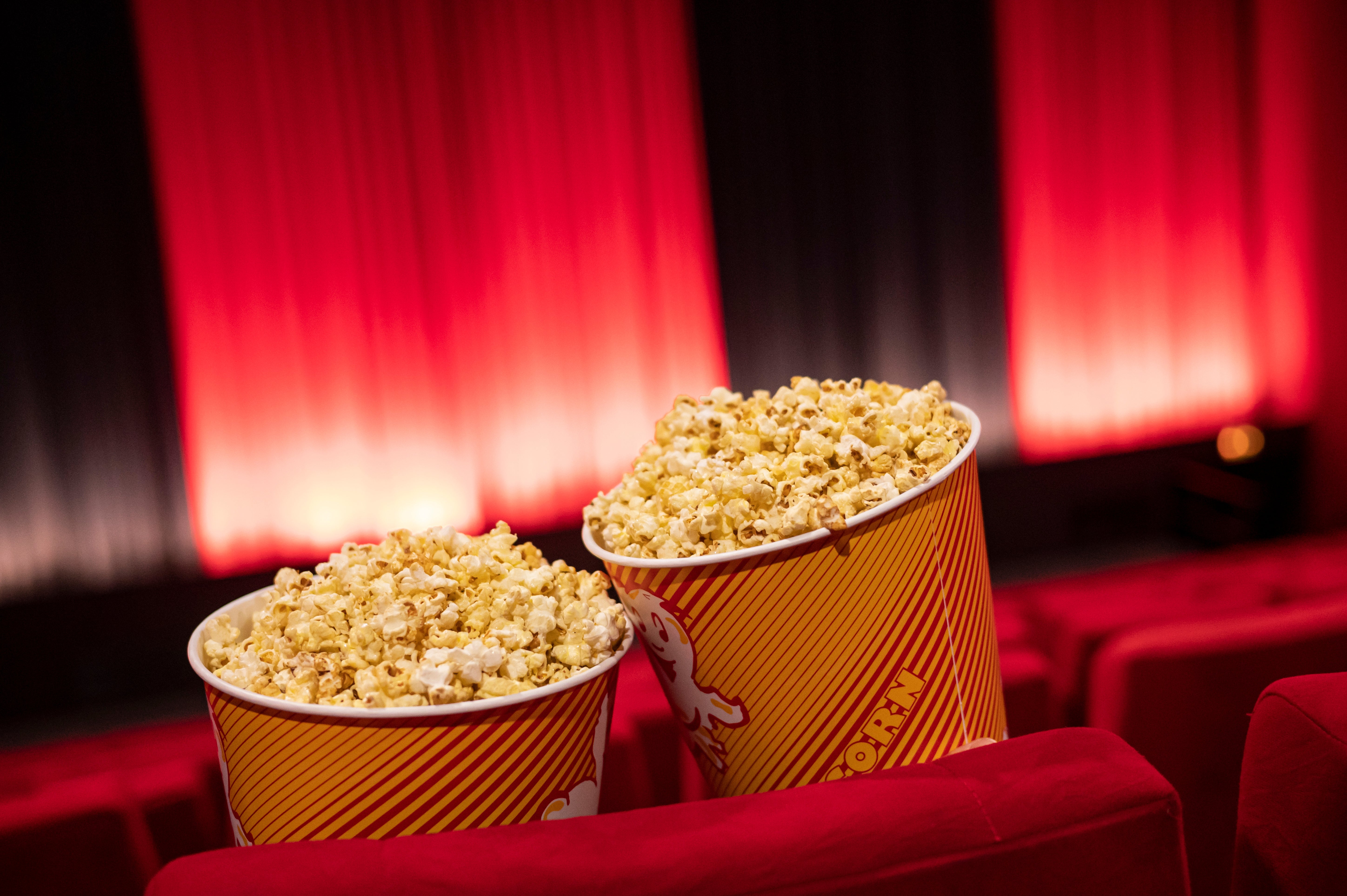Buckets of popcorn beryllium   connected  plush theatre  seats successful  a dimly lit cinema, with reddish  curtains lining the walls, evoking a classical  movie-going experience