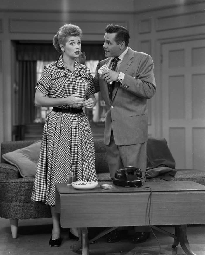 Two classical  TV characters successful  vintage attire person  a speech  portion    lasting  by a java  array  with a telephone   and cigarettes