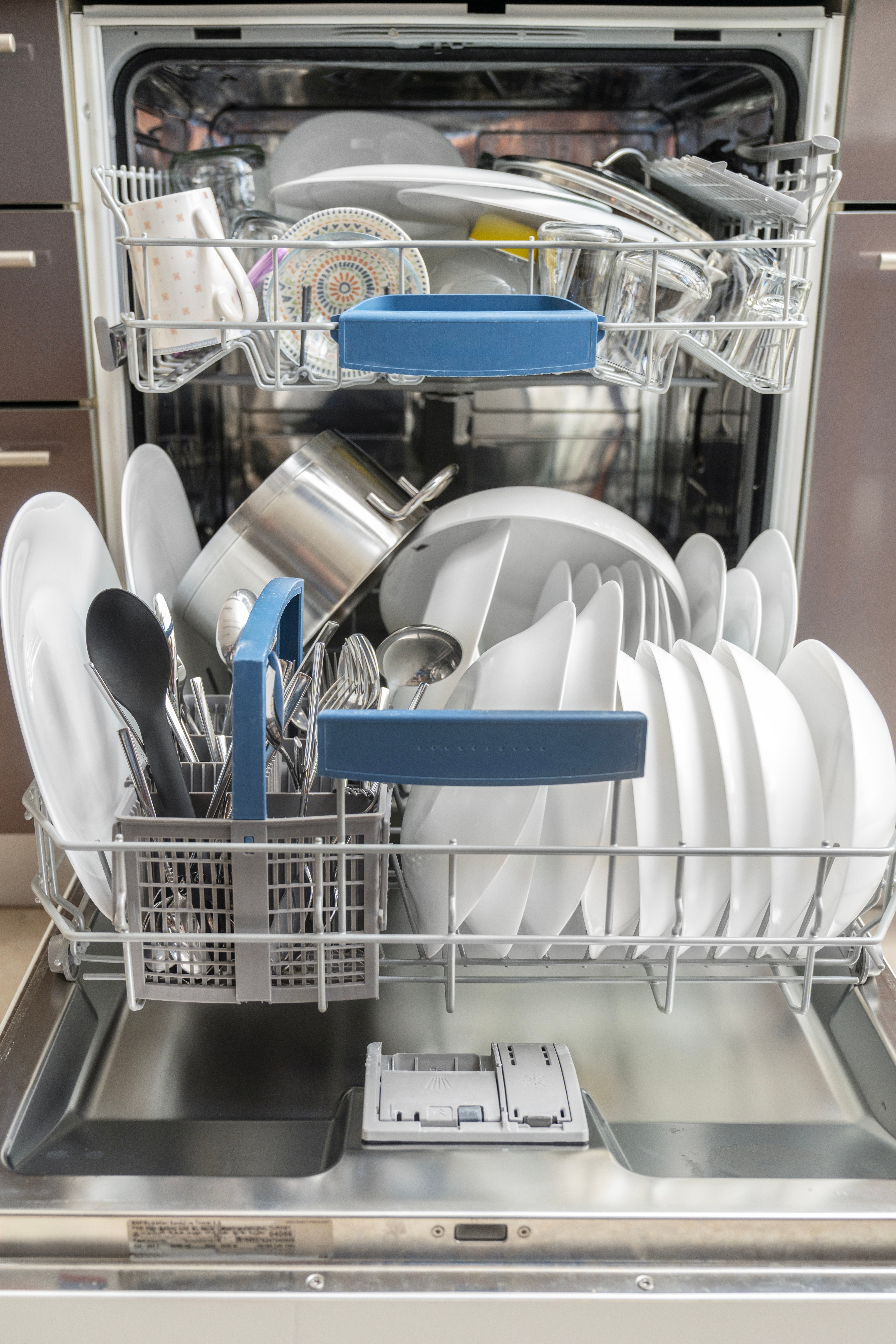 Open dishwasher with cleanable  plates, bowls, utensils, and cookware neatly arranged successful  2  racks