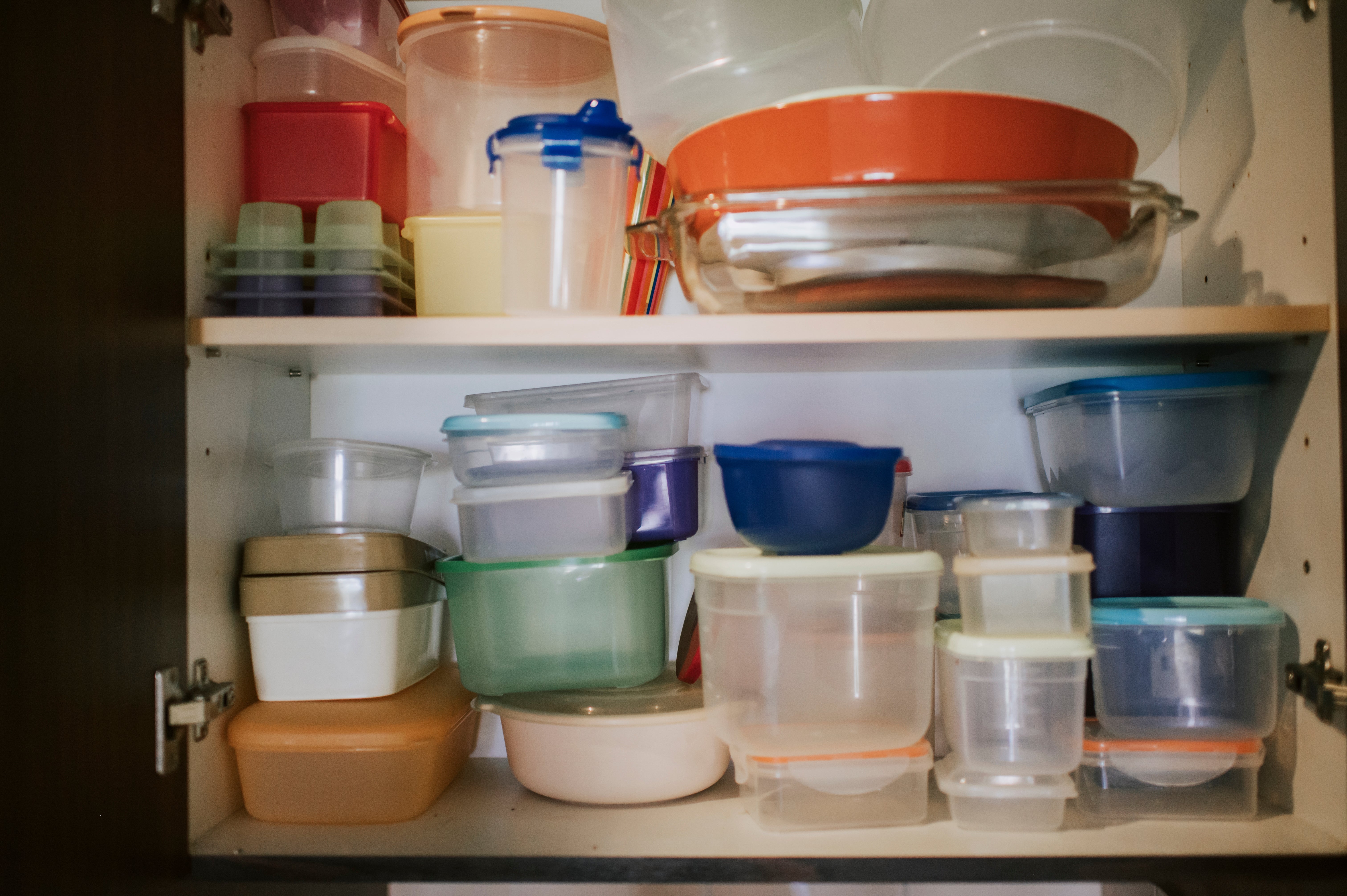 A cluttered room  furniture  filled with assorted  stacked integrative  nutrient  containers and bowls of antithetic  shapes and sizes