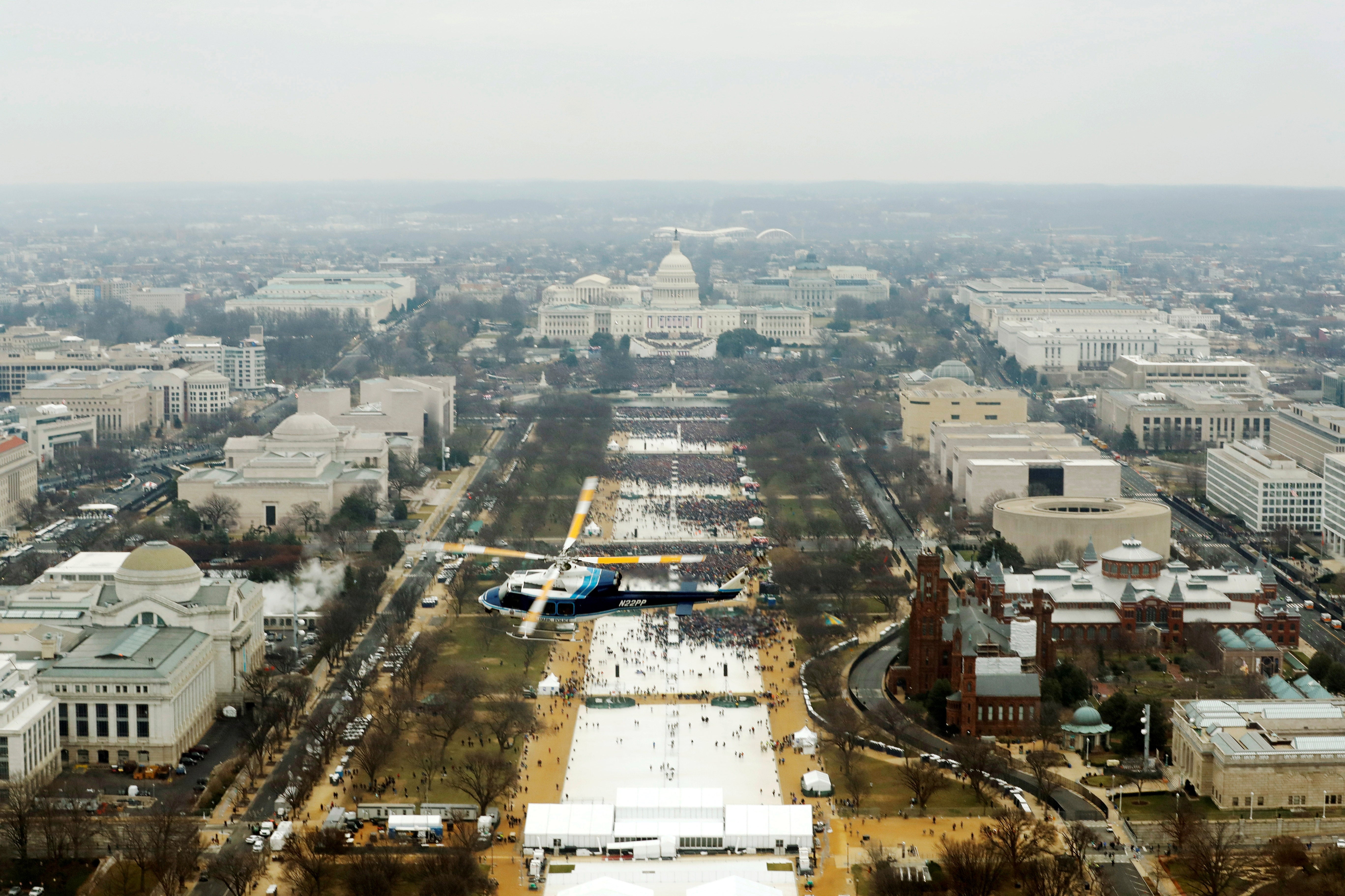 Pemandangan udara dari sebuah helikopter yang terbang di atas National Mall dengan US Capitol di kejauhan, dikelilingi oleh banyak orang