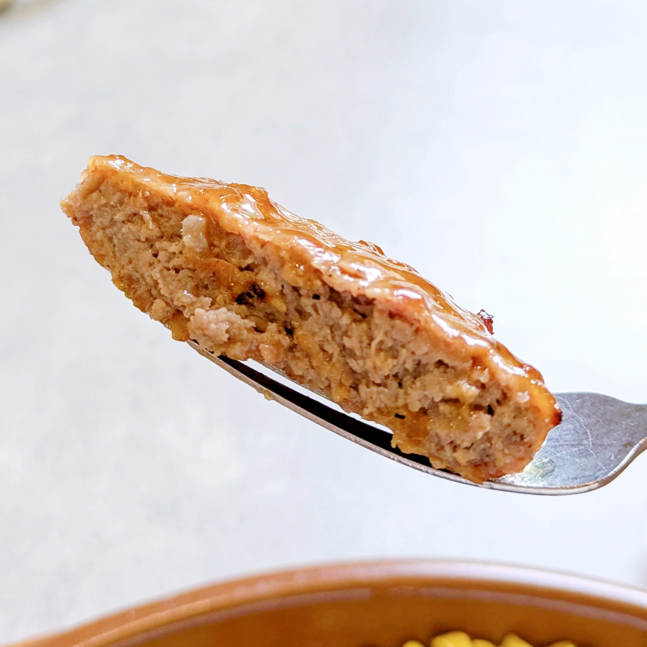 サイゼリヤ「オニオンソースハンバーグ」フォークに刺さったハンバーグの断面。ジューシーでおいしそうに見える。