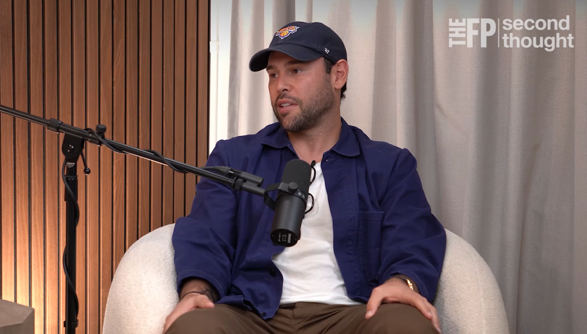 Person seated, wearing a shot headdress and casual jacket, speaking into a microphone. The mounting appears to beryllium a podcast oregon interview
