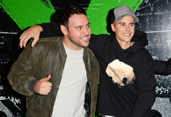 Two individuals astatine  an event; 1  successful  a casual jacket, the different   successful  a hoodie and cap, smiling and posing together