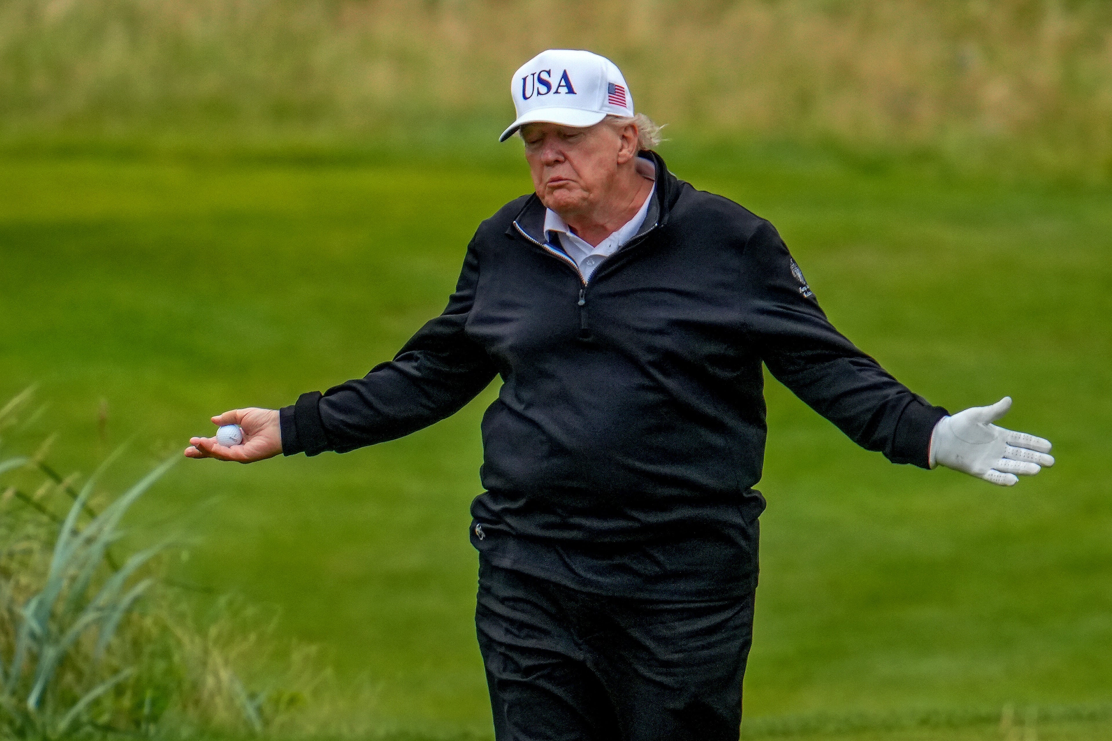 Orang yang bermain golf, memegang bola di satu tangan. Memakai a 