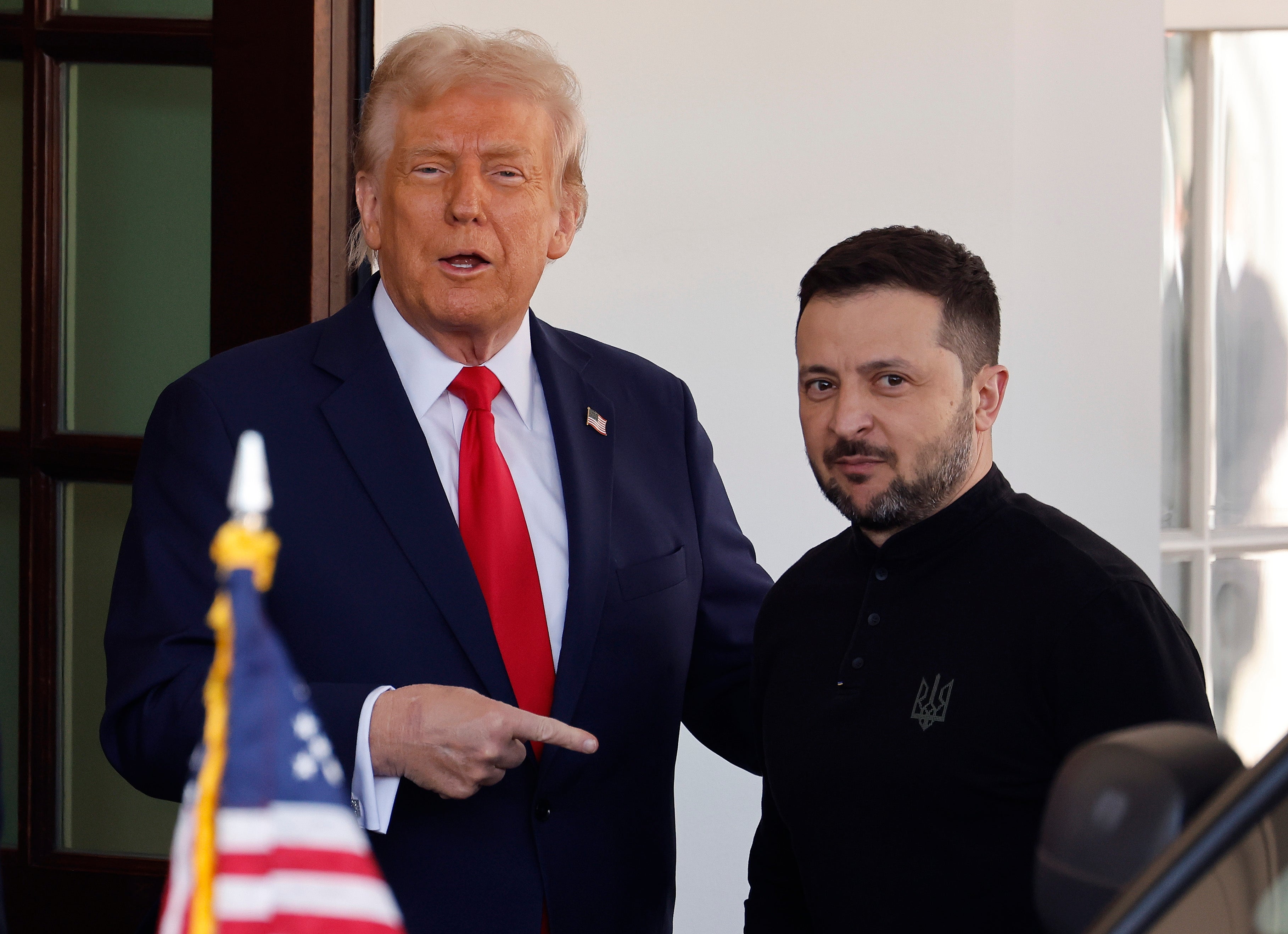 Dua orang berdiri bersama; satu poin sementara yang lain melihat ke depan. Bendera Amerika terlihat di latar depan