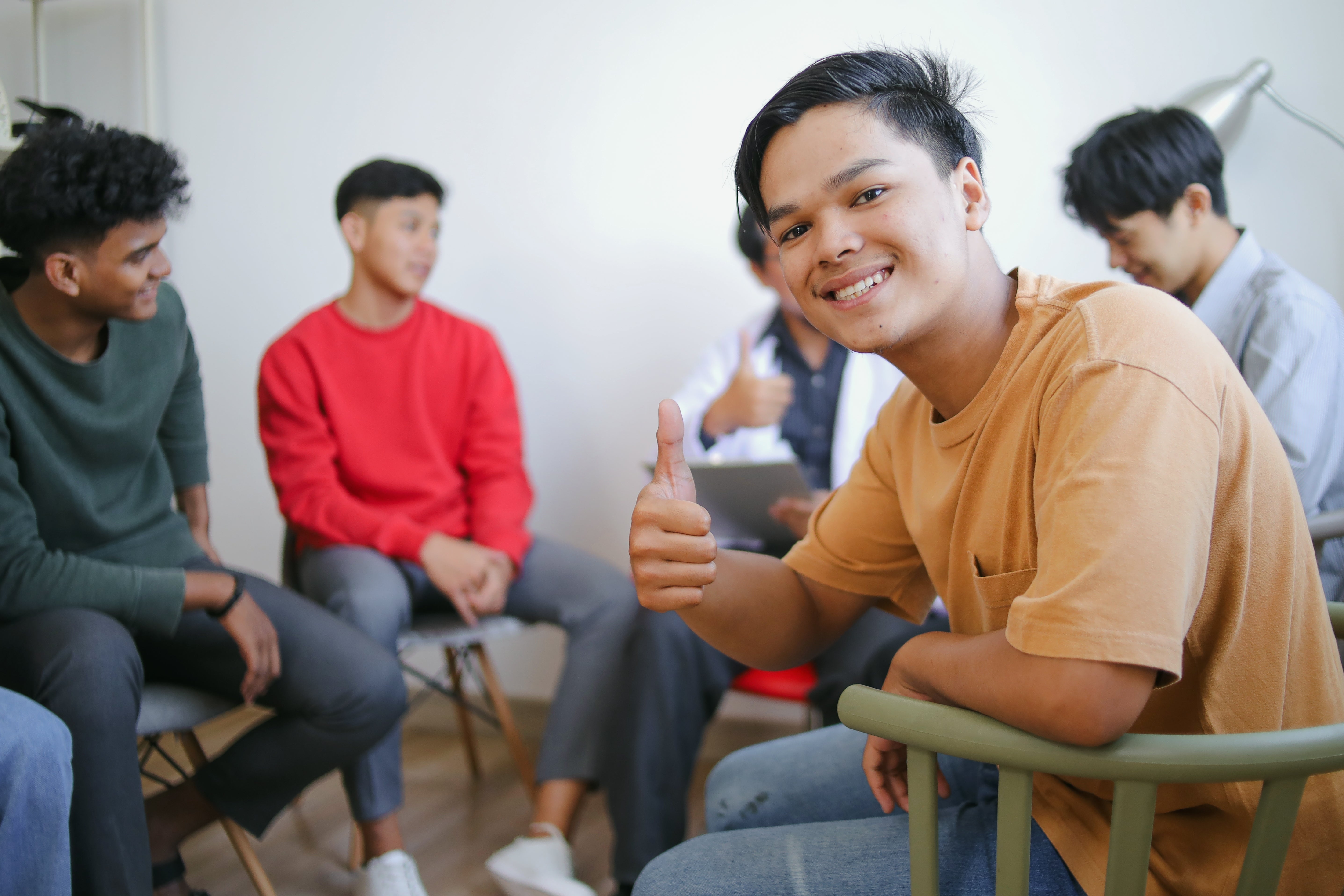 Person smiling and giving a thumbs-up successful  a casual radical  gathering  with others focused elsewhere