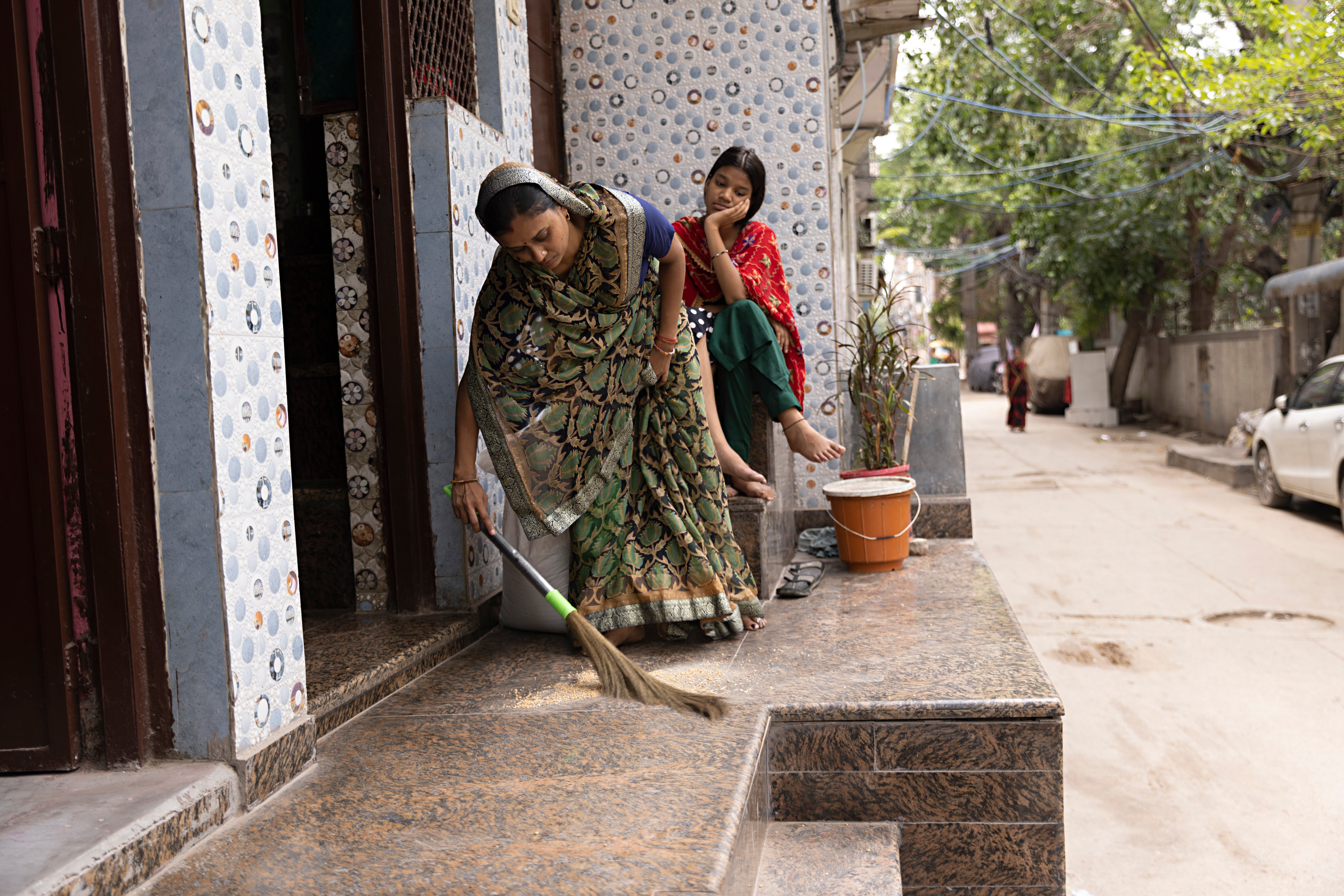 A pistillate   sweeps extracurricular  her location   portion    a young miss  sits nearby, smiling
