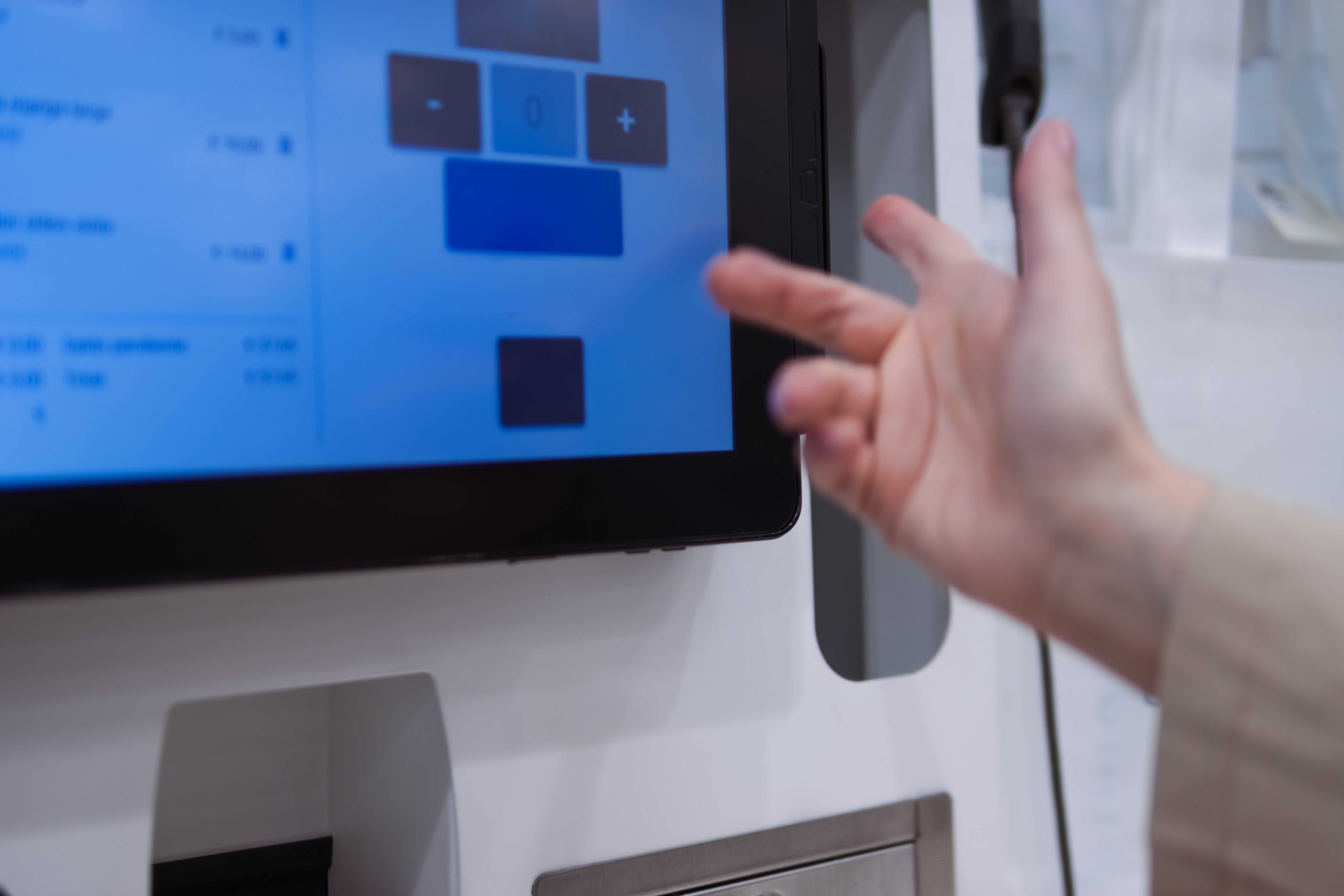 Orang yang menggunakan layar sentuh dengan tangan terlihat, berinteraksi dengan tampilan menu di kios atau layar elektronik