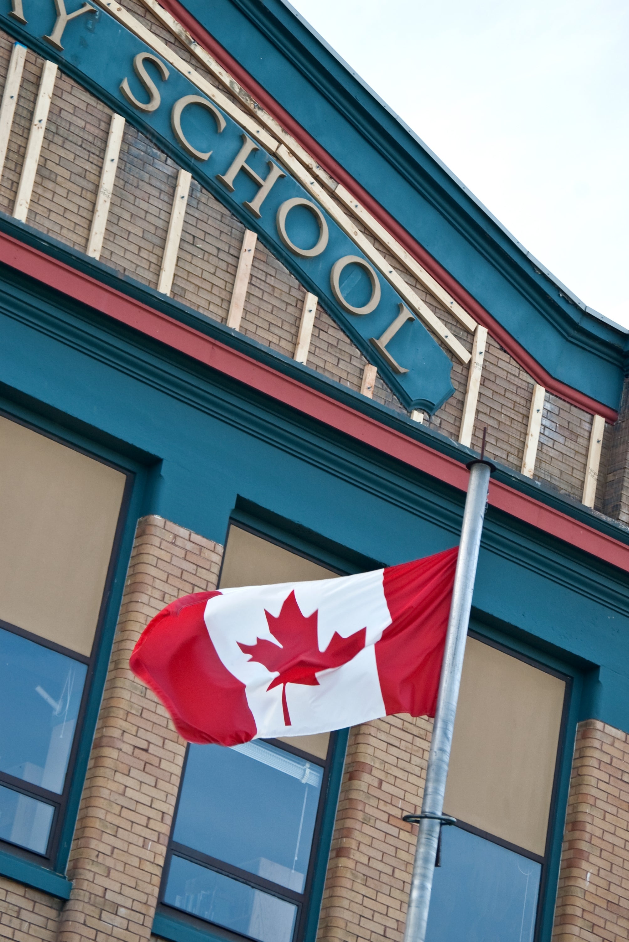 Canadian flag waving in front of a brick building with "Elementary School" sign