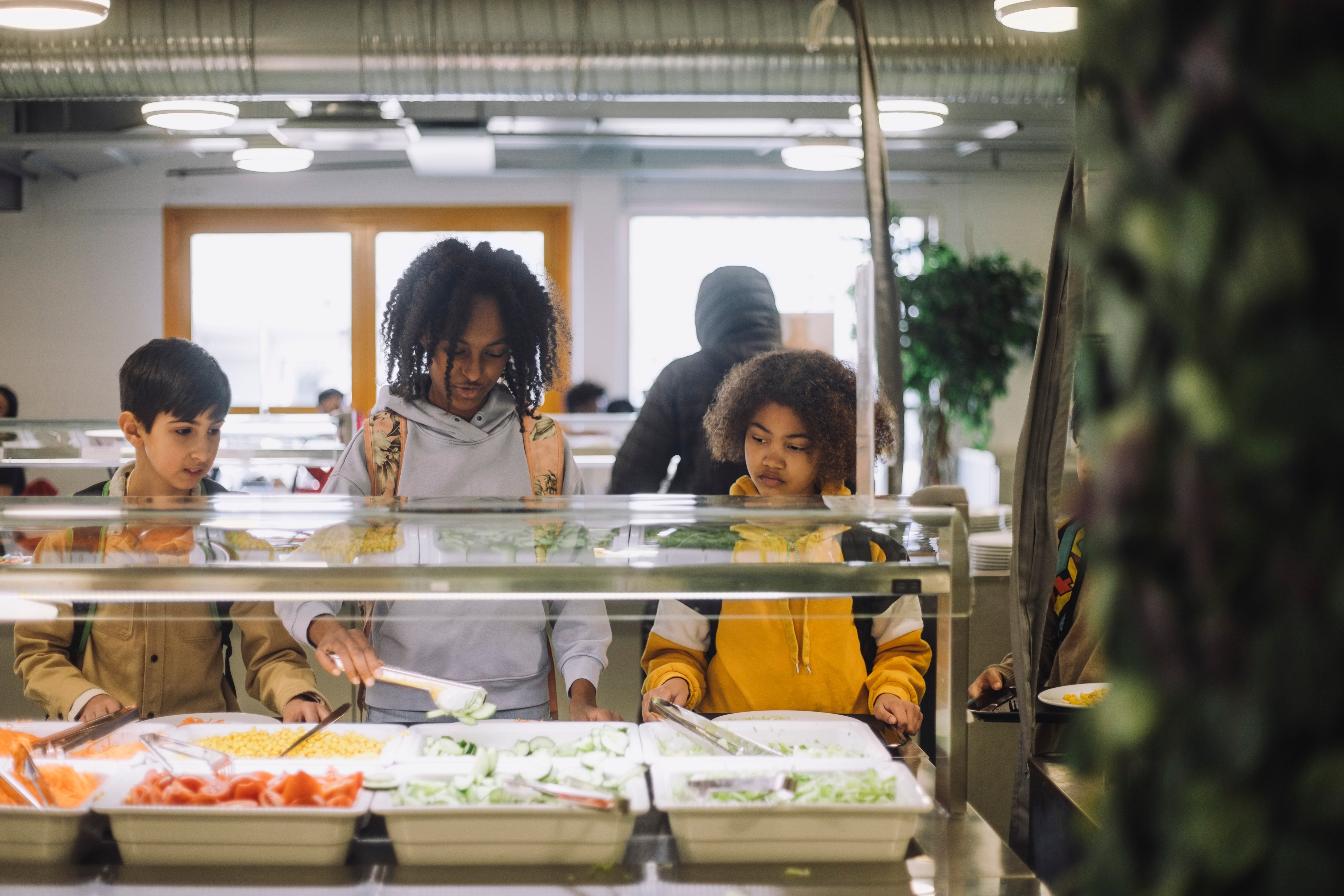 Children selecting food from a cafeteria salad bar, focusing on healthy options