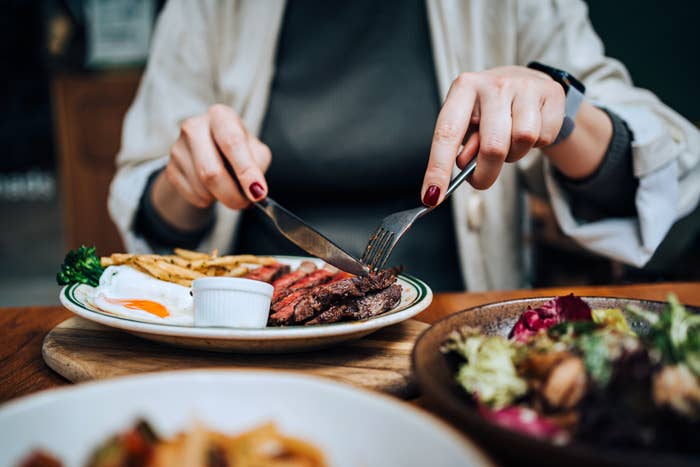 Person utilizing fork and weapon  to devour   steak with fries connected  a plate, crockery   connected  the side
