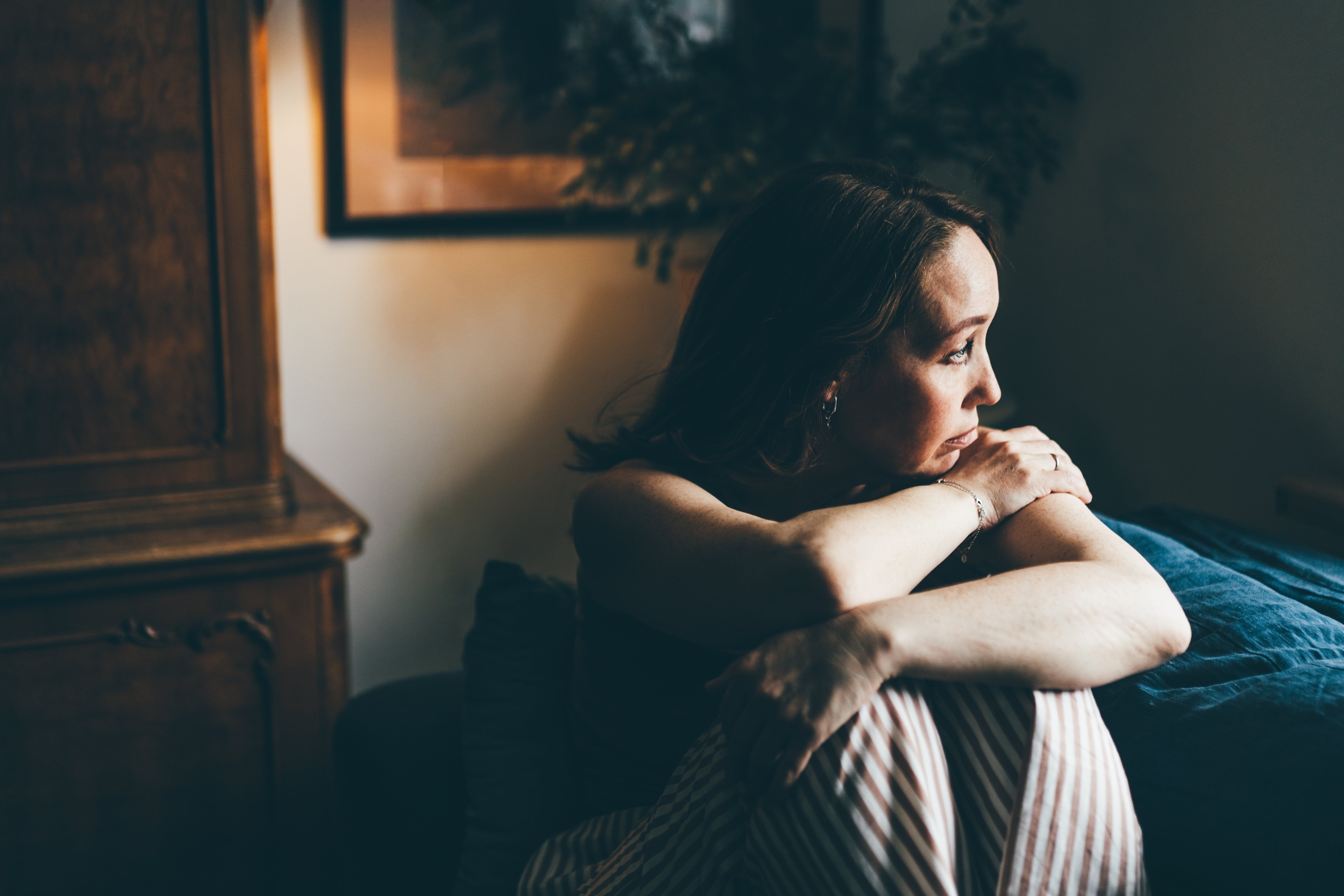 Person sitting thoughtfully connected a sofa, gazing out, suggesting contemplation oregon introspection, applicable to a health-related topic
