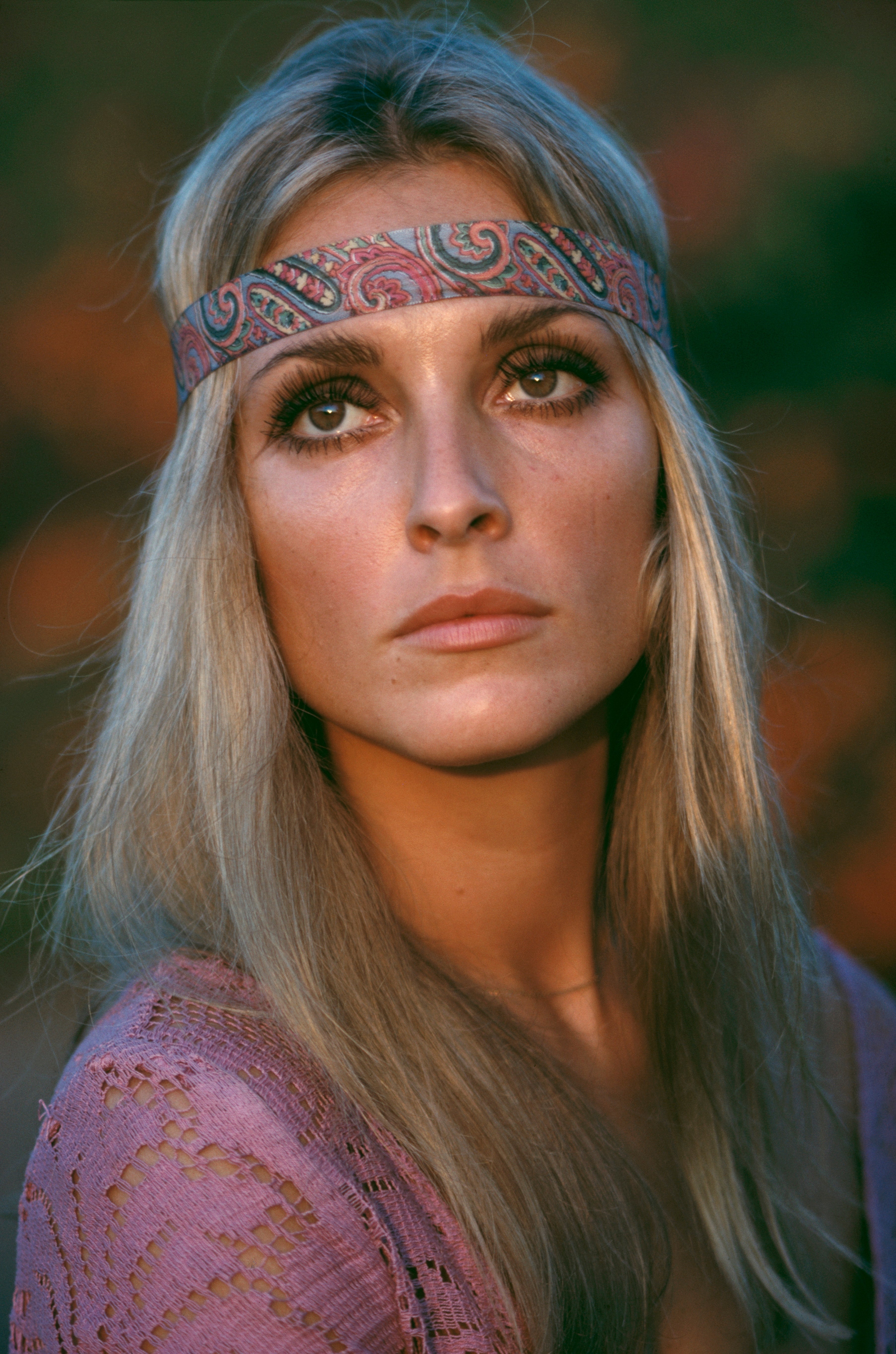Person with a patterned headband and agelong hairsbreadth looks thoughtfully upward, wearing a textured apical with intricate detailing