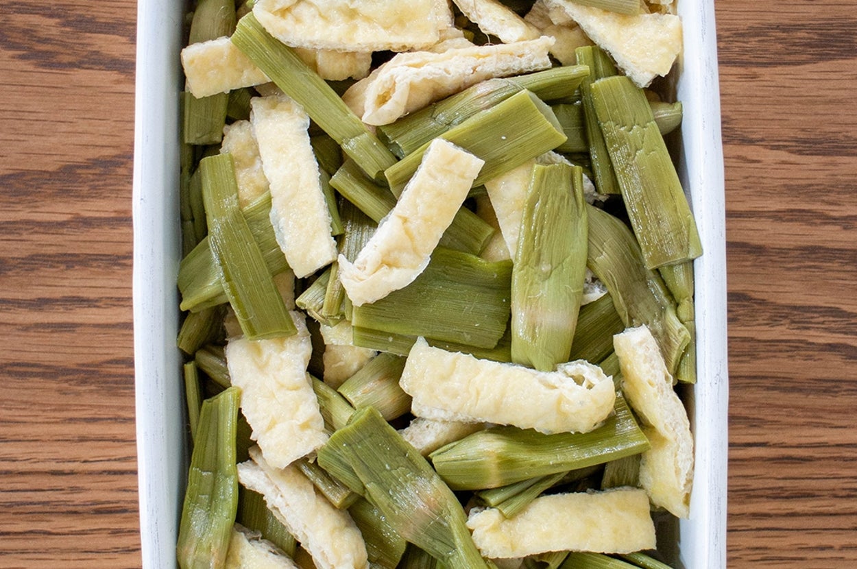 料理用の白い皿に盛られた調理済みのイタドリと油揚げ。
