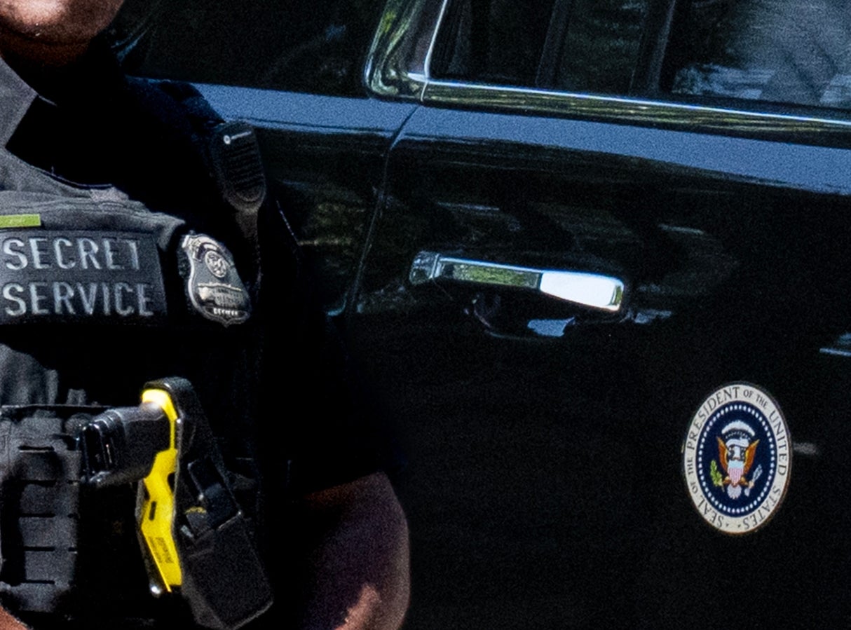 En Secret Service-agent står våken ved siden av et presidentkjøretøy med en passasjer synlig inni