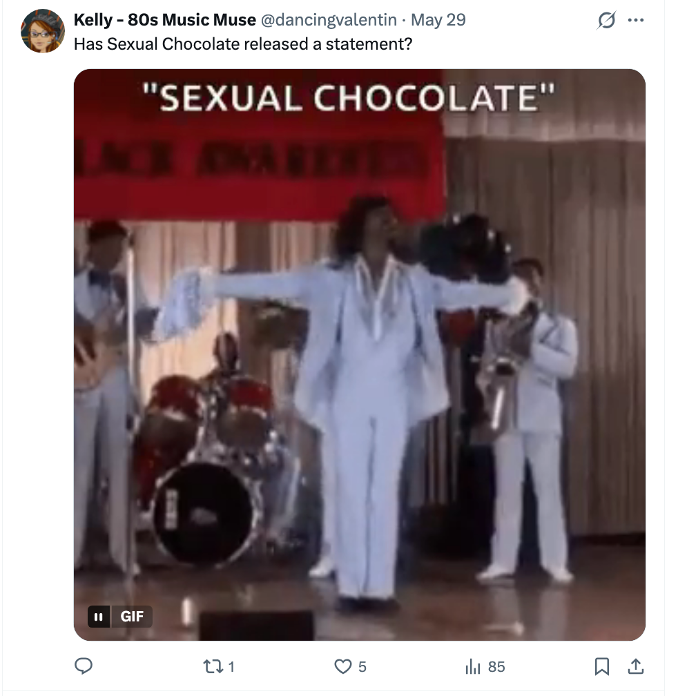 A idiosyncratic   connected  signifier    wearing a shiny suit, arms outstretched, with a set  playing down  them. Text reads "Sexual Chocolate."