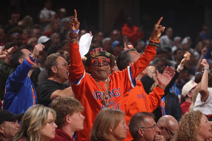 A idiosyncratic   enthusiastically cheers astatine  a sports event, wearing a colorful sports-themed outfit and glasses, surrounded by a cheering crowd