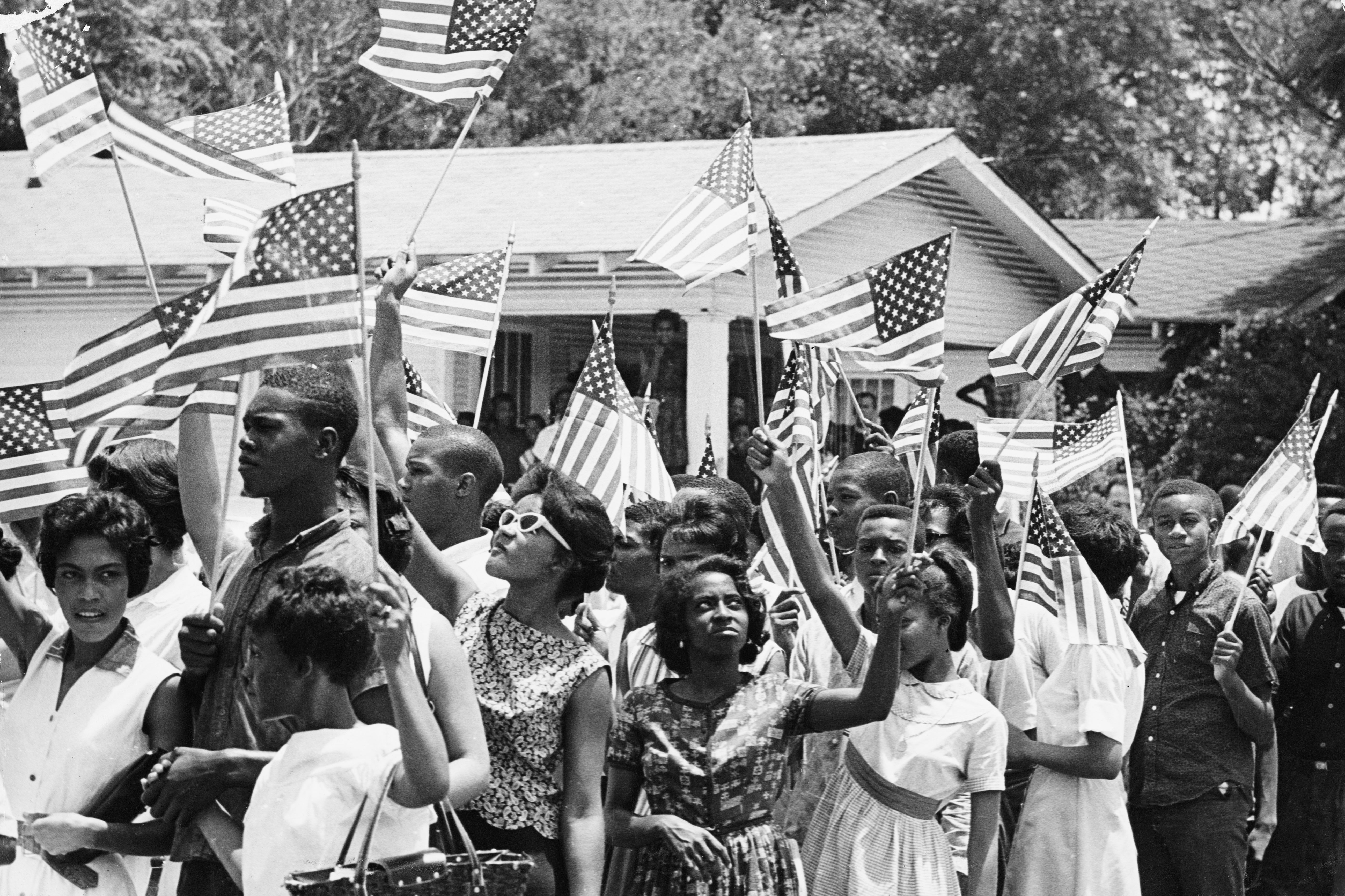 A radical  of people, including children, clasp  American flags successful  a peaceful gathering extracurricular  a house, evoking a country   of unity and patriotism