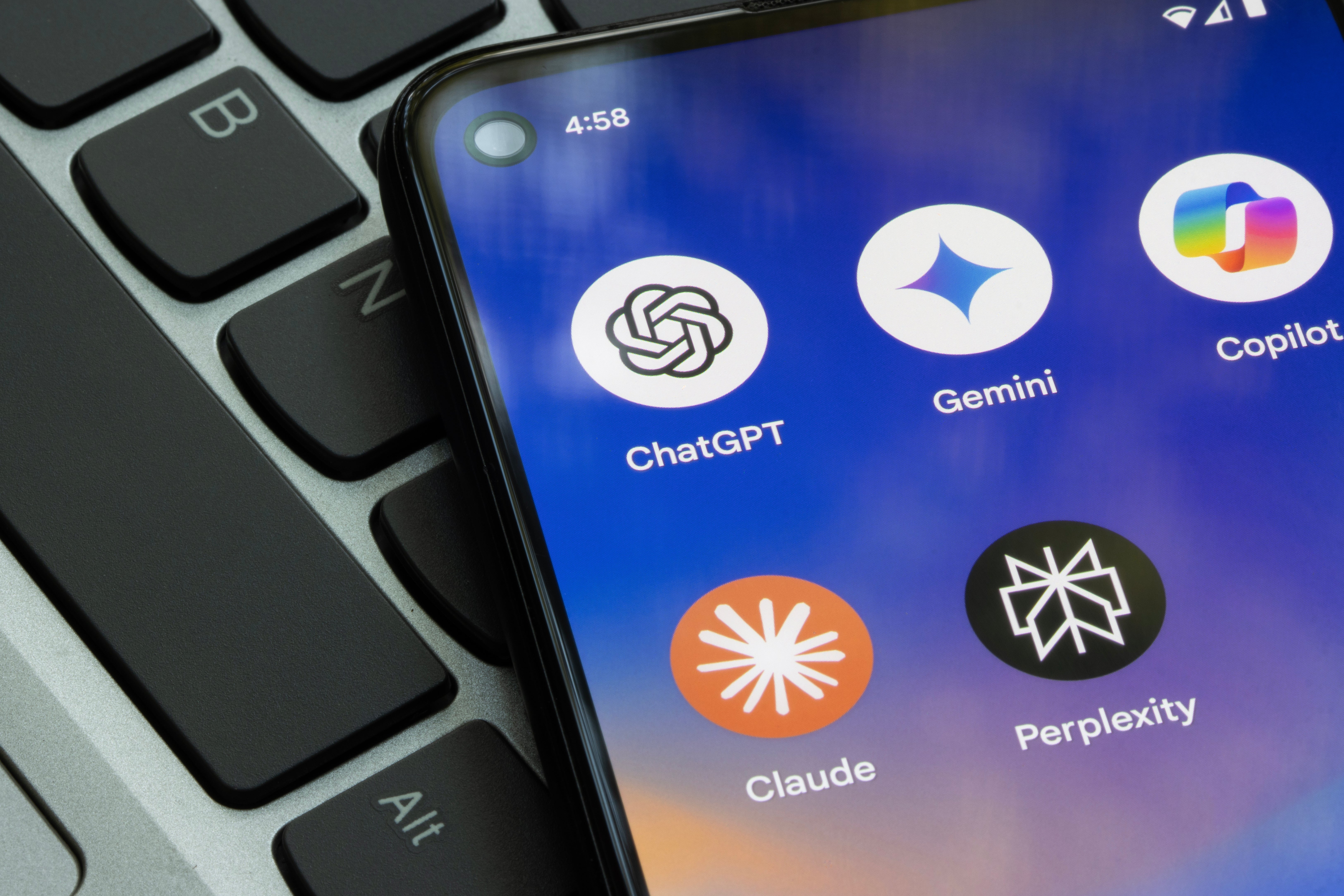  ChatGPT, Gemini, Copilot, Claude, and Perplexity, placed connected  a laptop keyboard
