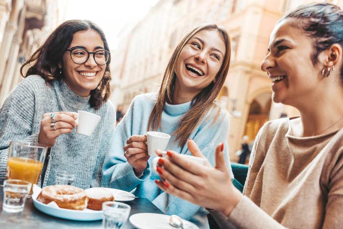 Three friends enjoying drinks and pastries astatine  an outdoor café, smiling and chatting