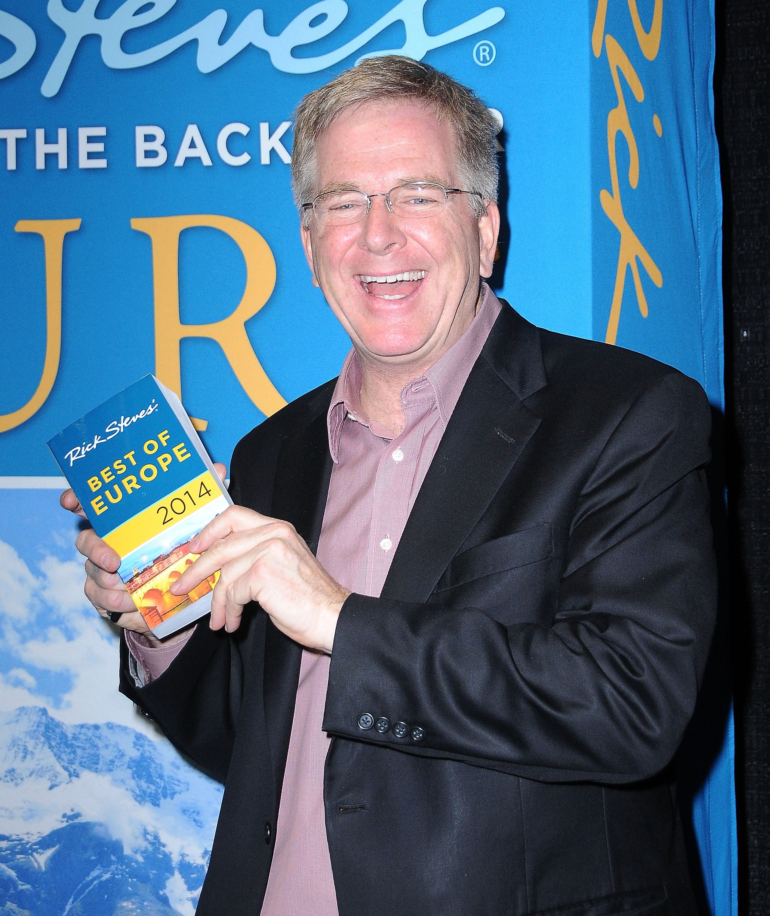 A idiosyncratic   smiling portion    holding a question   guidebook titled "Best of Europe 2014" by Rick Steves