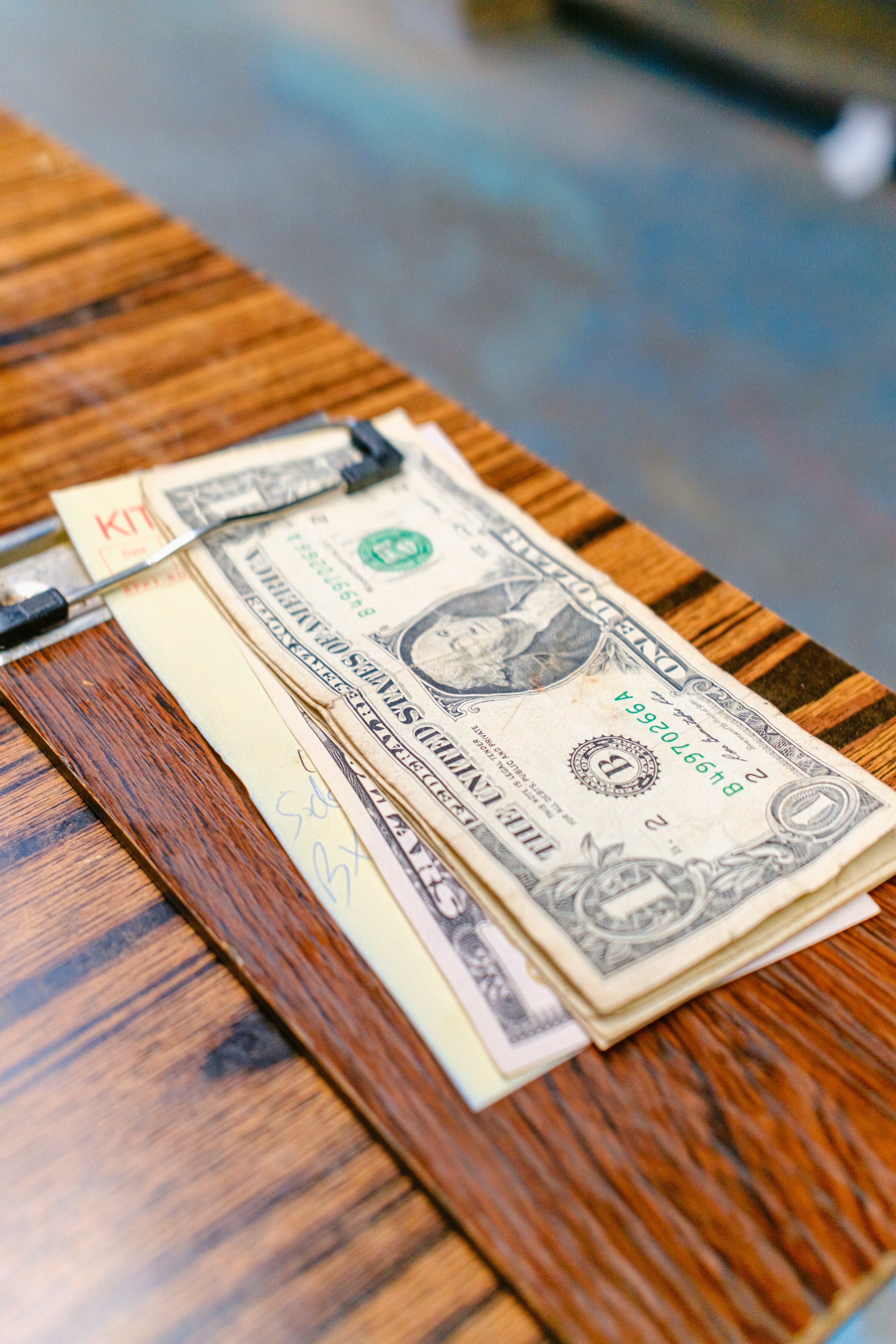 Money and papers connected  a woody  table, with a pen resting connected  top