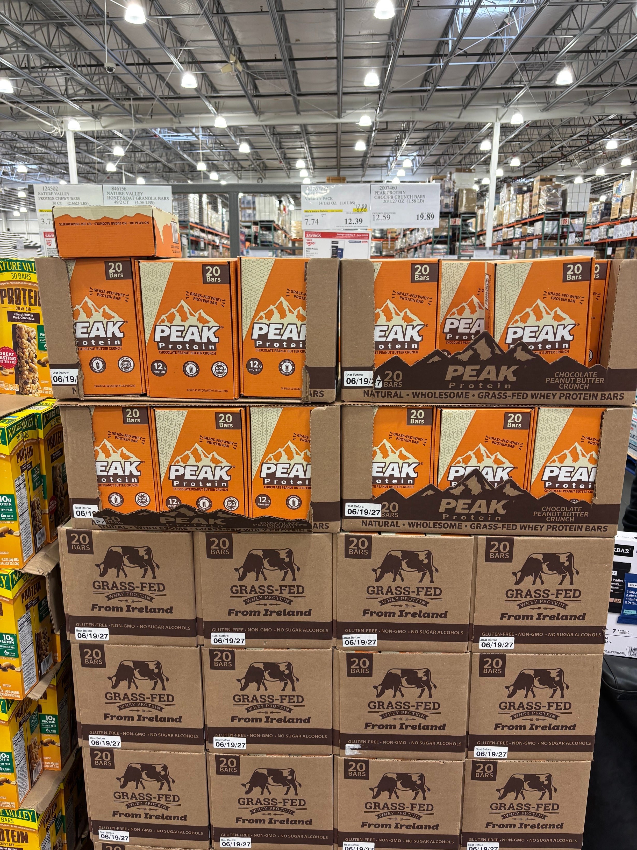 Boxes of Peak protein bars are stacked in a warehouse store aisle