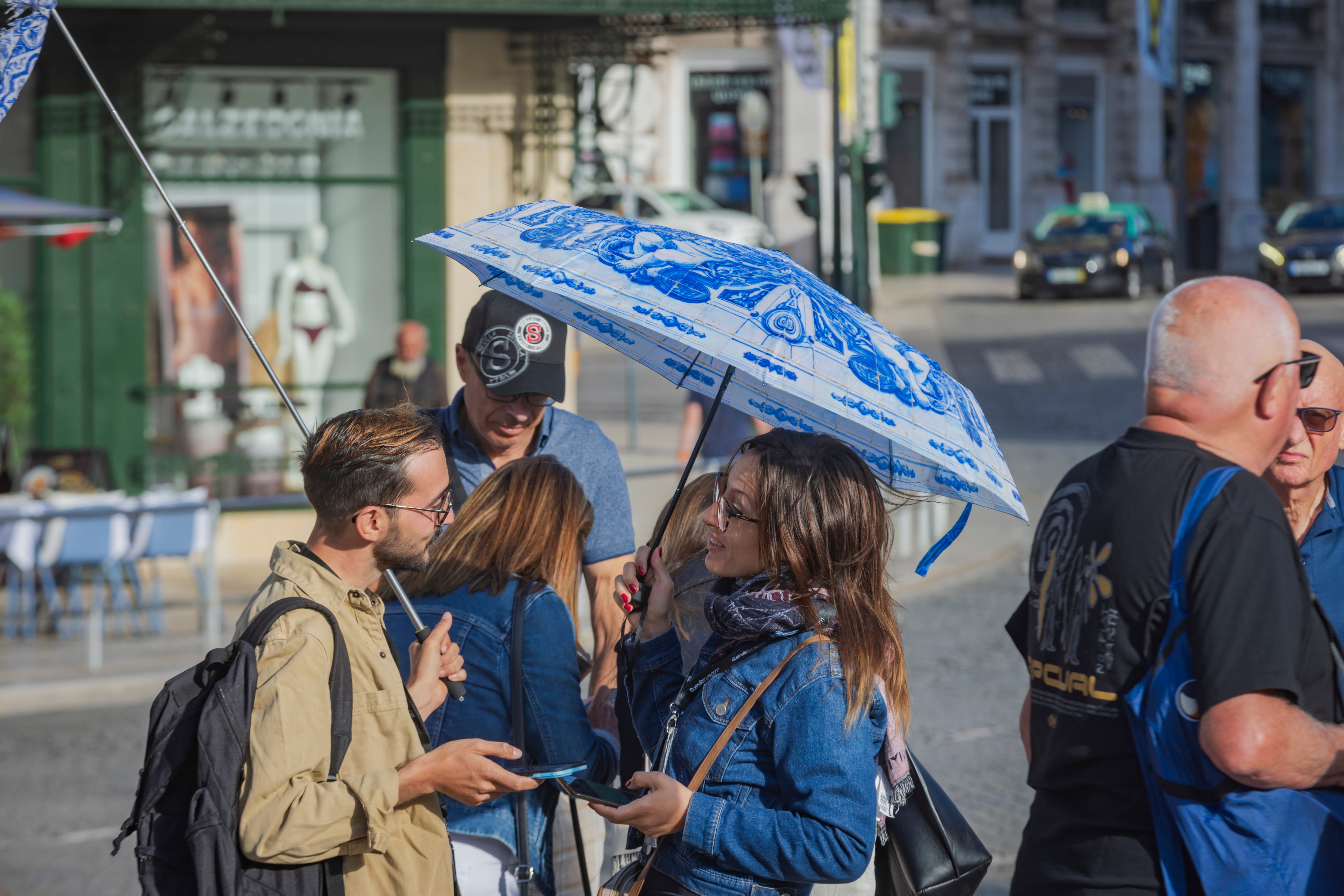 People gathered outdoors, immoderate   holding umbrellas and utilizing smartphones, engaged successful  conversation. Urban mounting  successful  the background