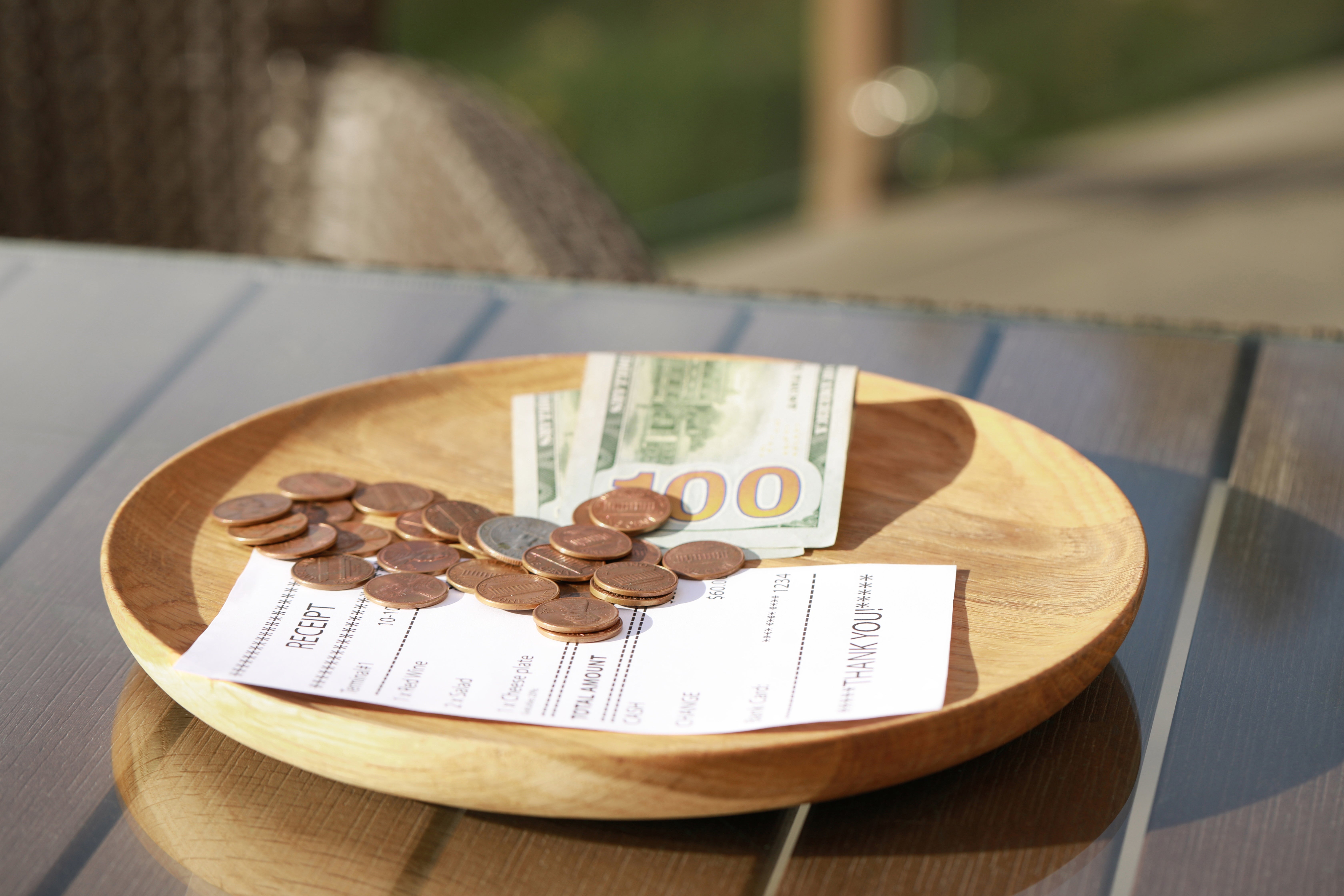 A woody  tray connected  a array  holds respective  coins, a $100 bill, and a receipt