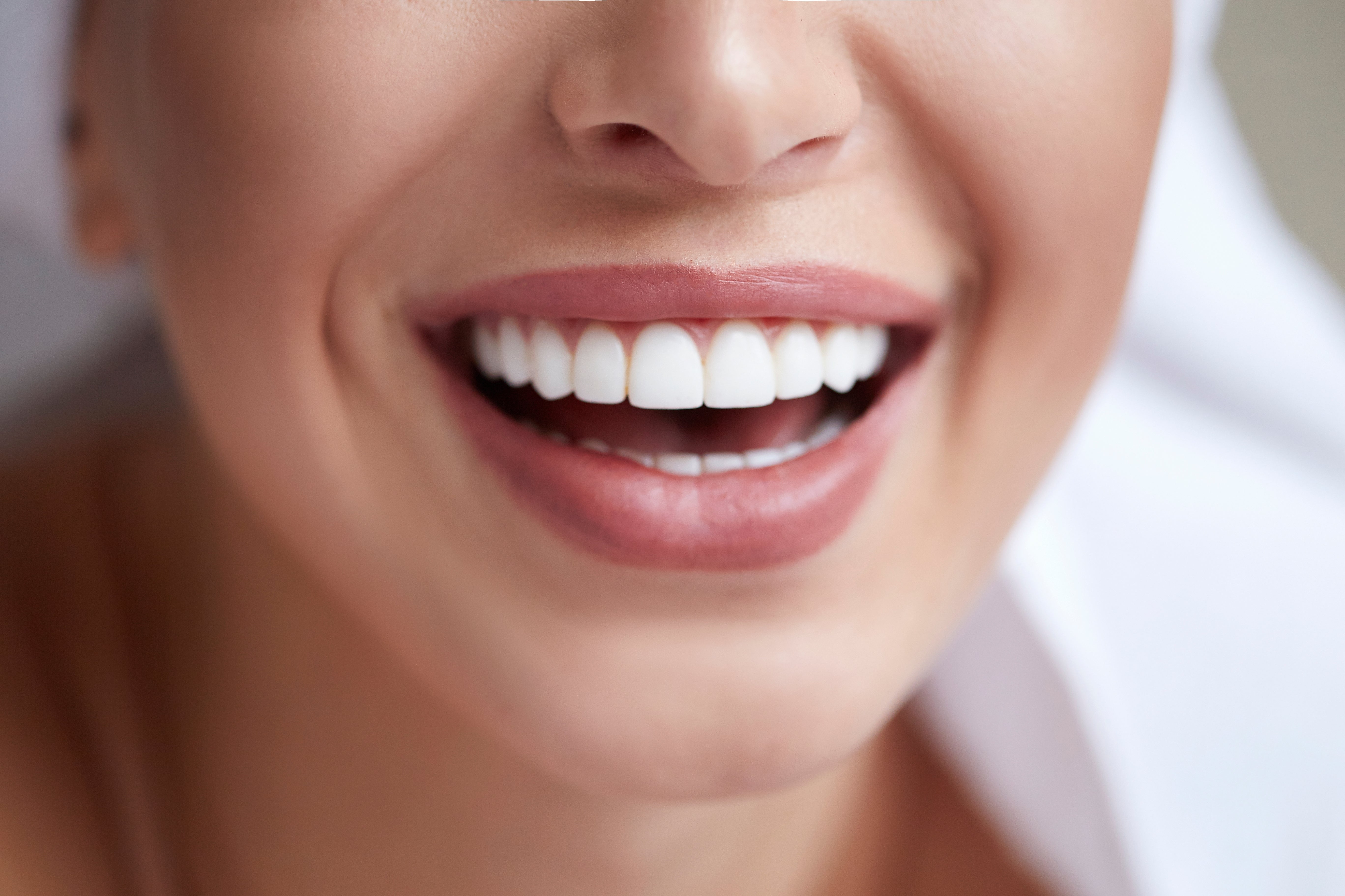 A close-up of a idiosyncratic   smiling, showing bright, achromatic  teeth. The idiosyncratic   exudes happiness and the representation  focuses connected  the rima  area