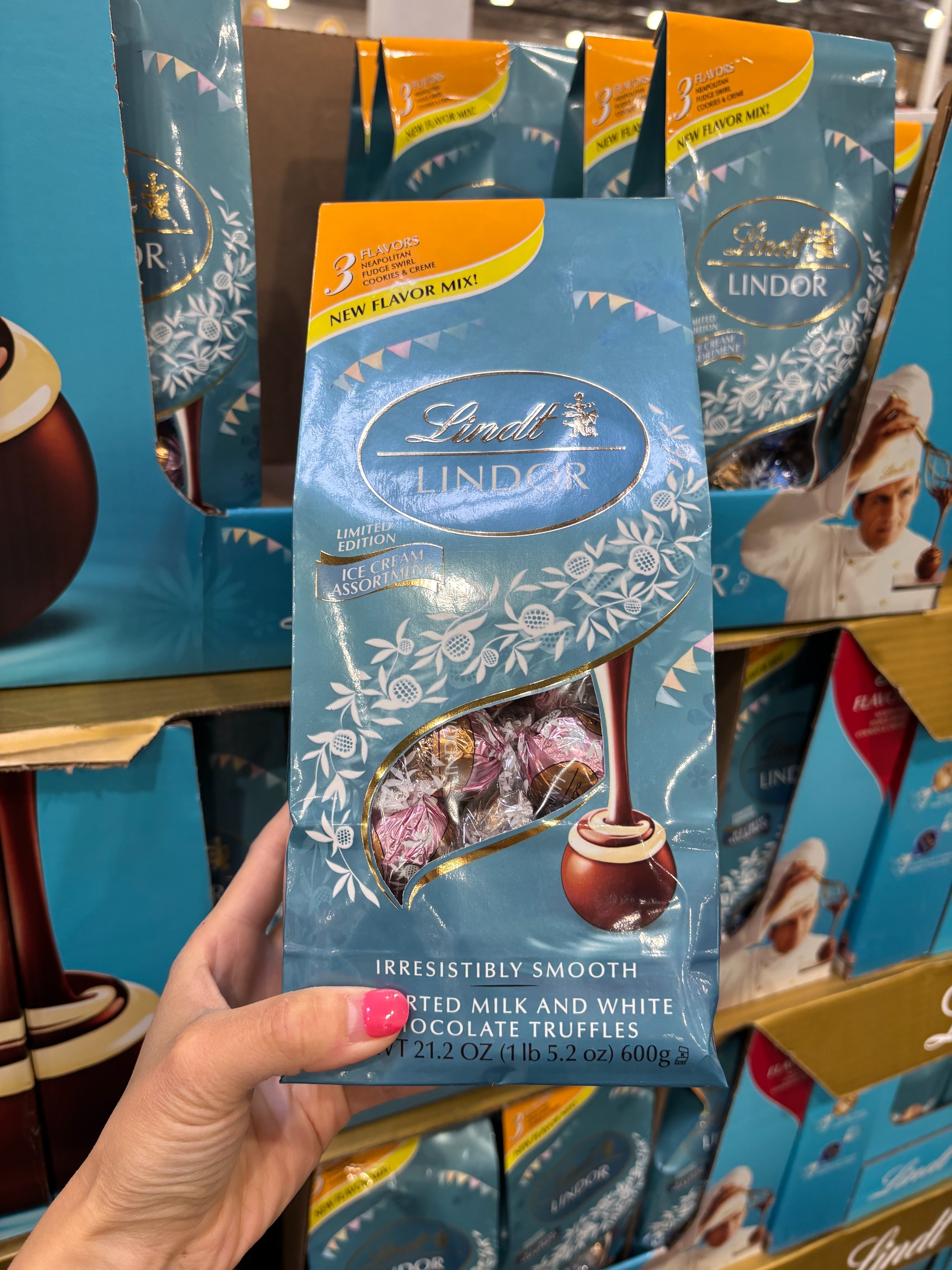Hand holding a package of Lindt Lindor limited edition milk and white chocolate truffles at a store display