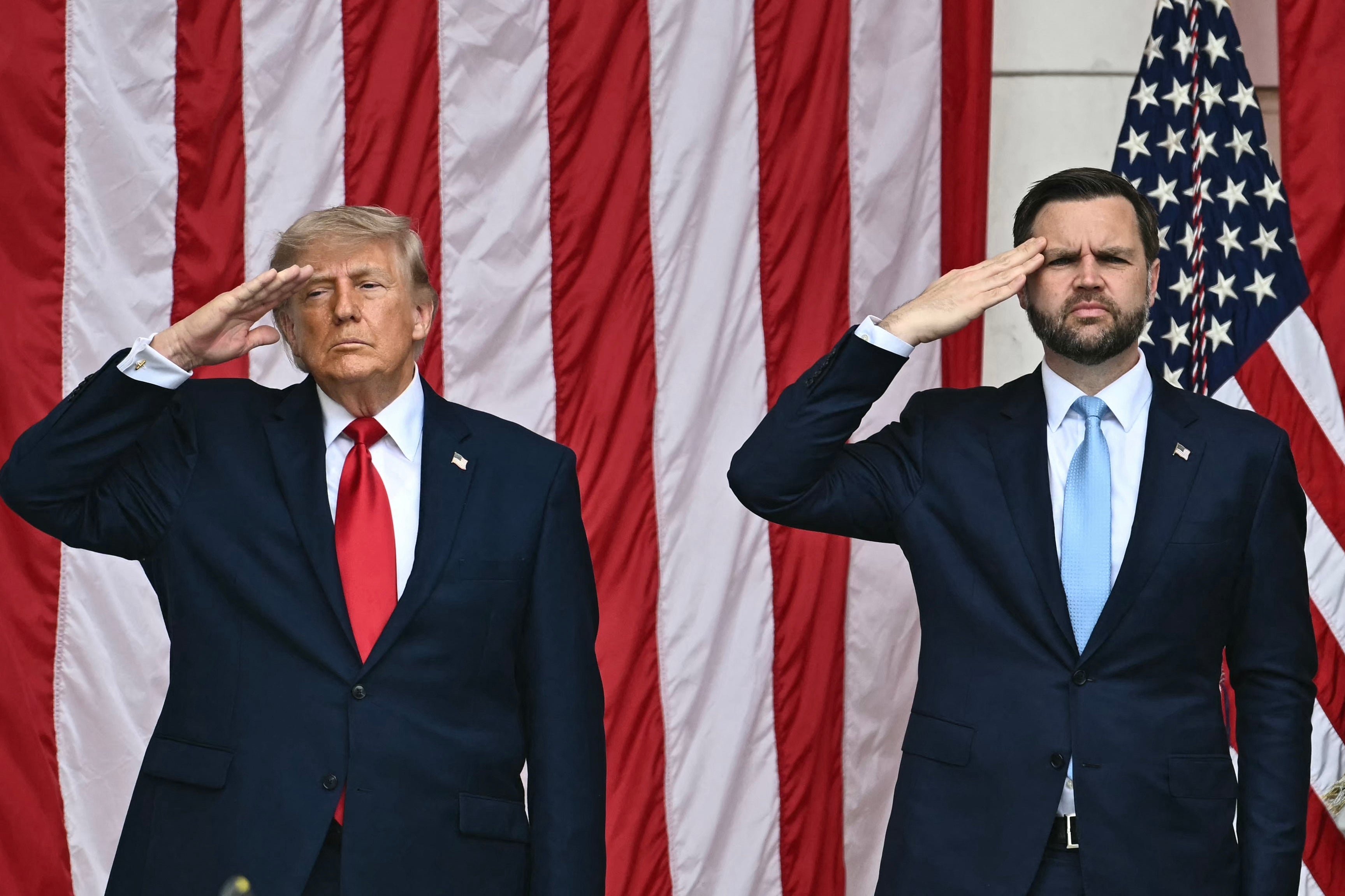 Two men successful suits are lasting and saluting successful beforehand of large, vertical-striped flags