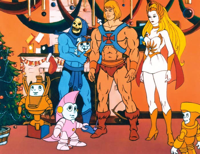 Animated characters He-Man, She-Ra, and Skeletor stand in a festive setting with decorations and two robot companions