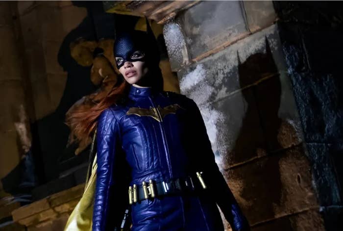 Person successful  a superhero costume with a disguise  and cape stands dramatically successful  beforehand   of a chromatic  wall