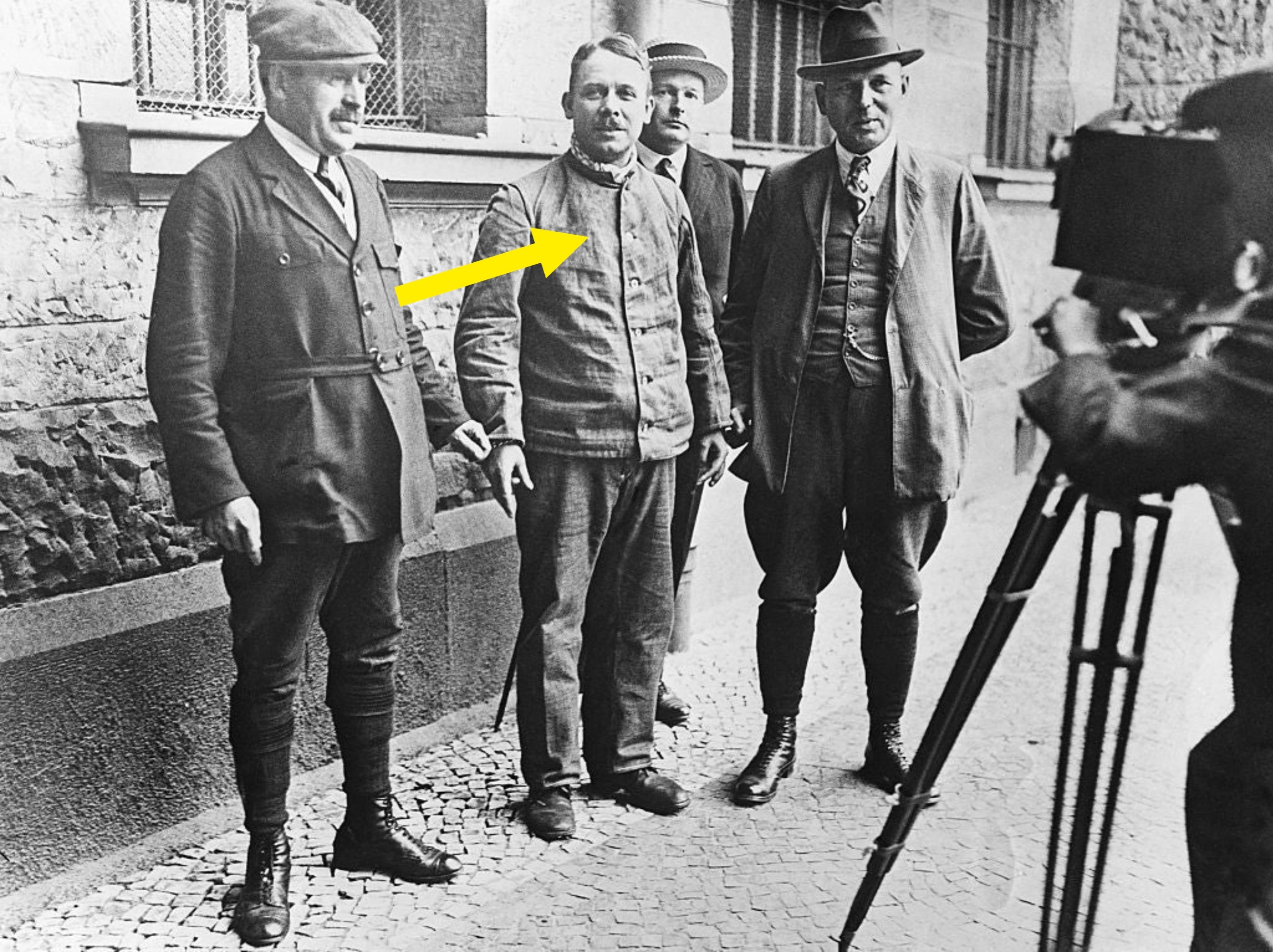 Four men airs  for a photograph  outside. One antheral   operates a camera connected  a tripod successful  the foreground. The men deterioration  aboriginal  20th-century attire