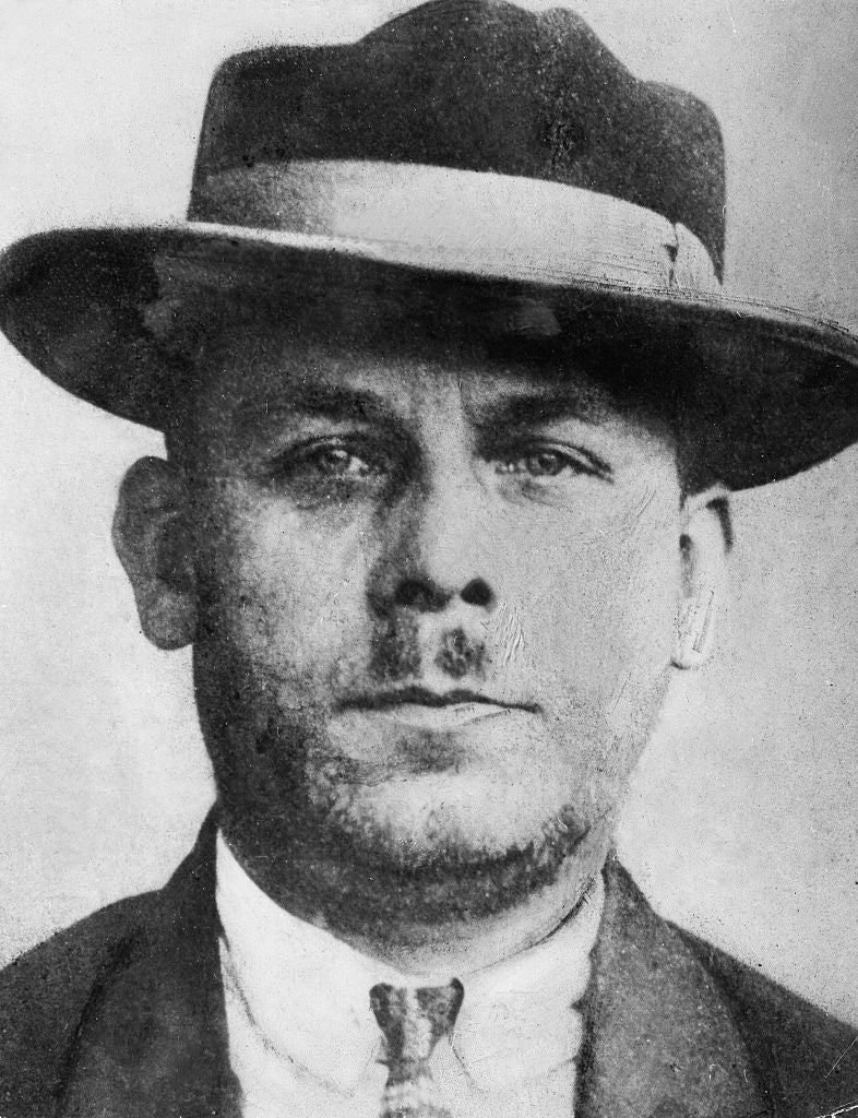 A achromatic  and achromatic  photograph  of a antheral   wearing a suit, tie, and hat, with a neutral expression