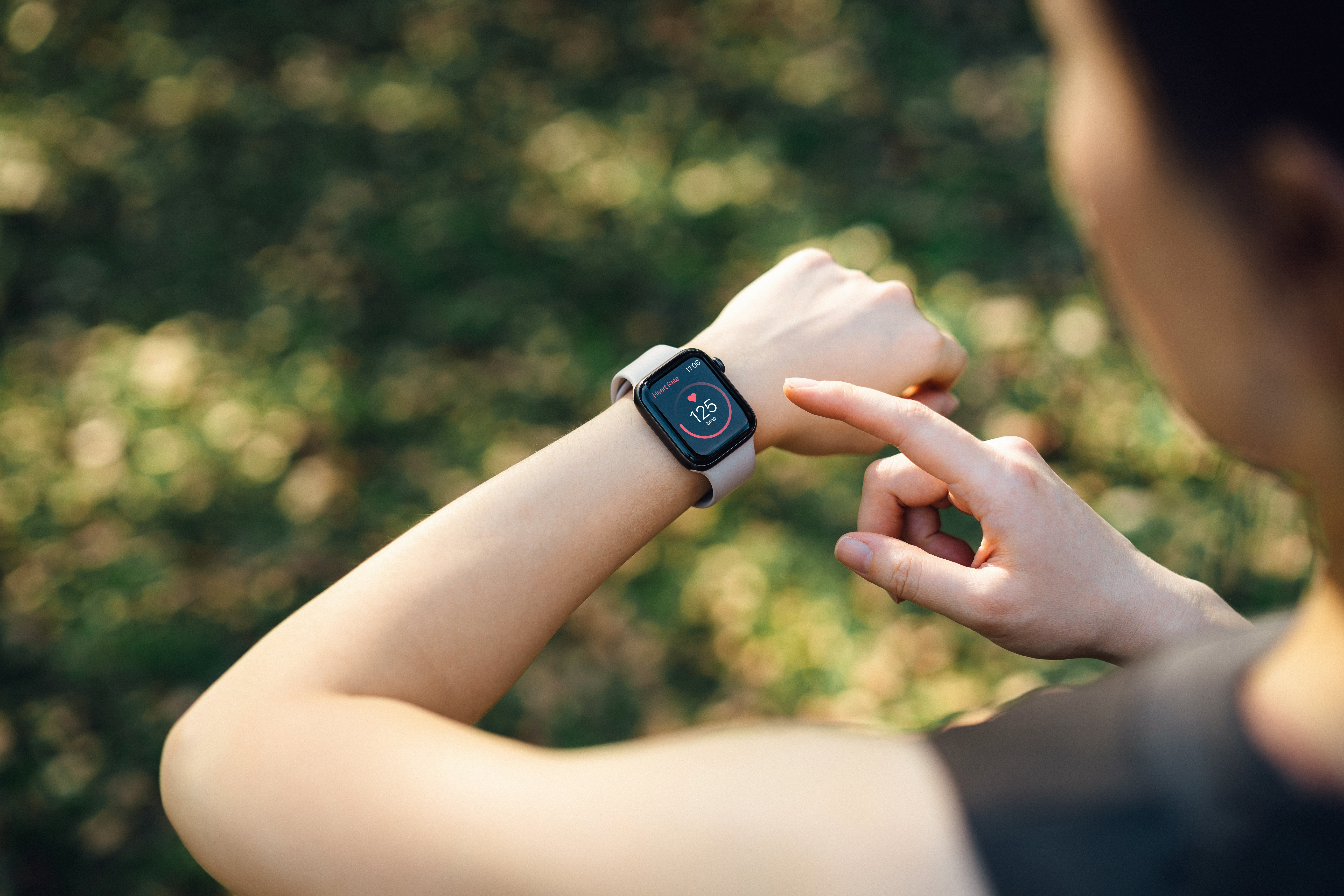 Person checking fittingness  tracker connected  wrist, displaying steps and bosom  rate, outdoors
