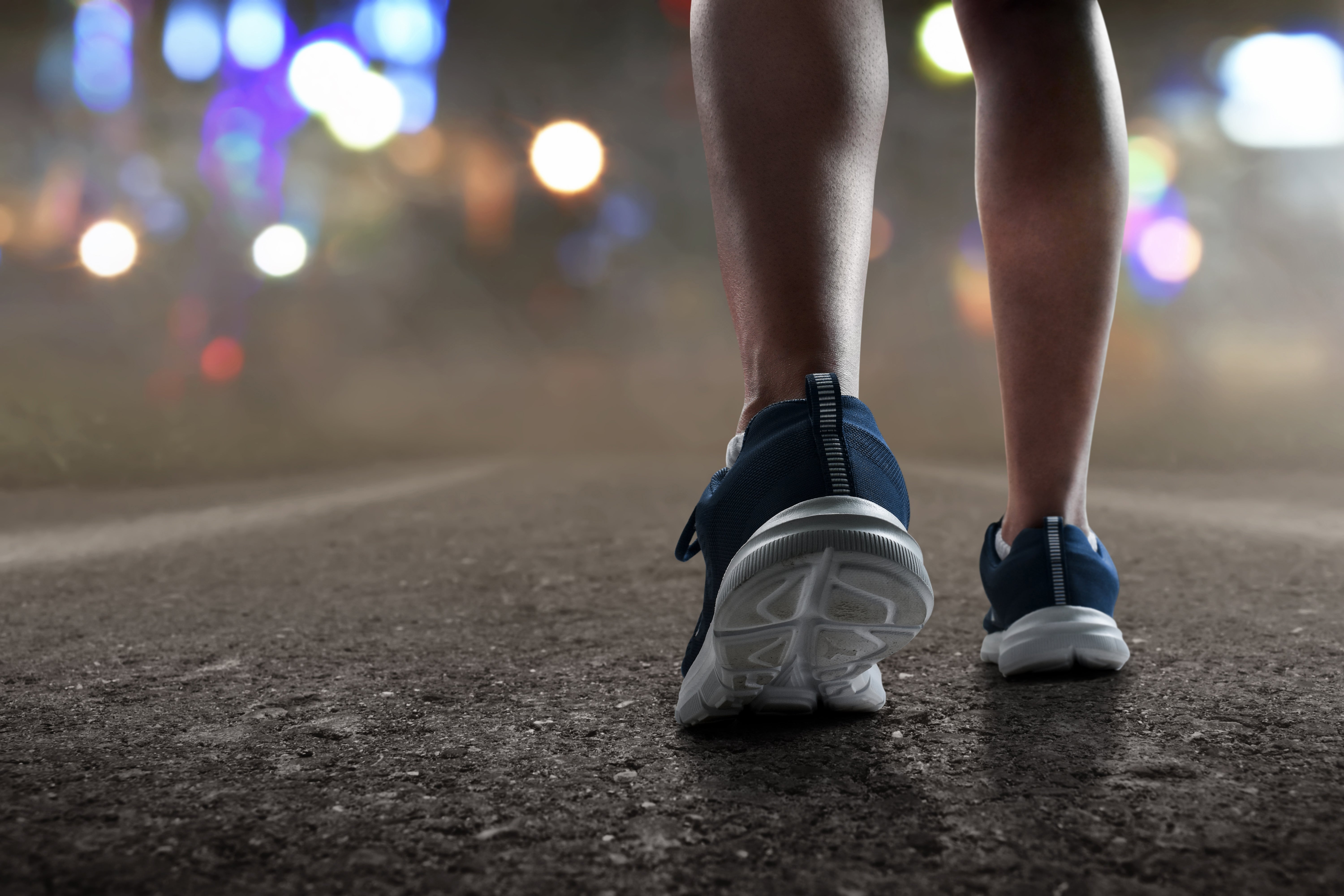 Person wearing diversion  shoes lasting  connected  a road, with blurred lights successful  the background, suggesting a absorption   connected  fittingness  oregon  walking astatine  night