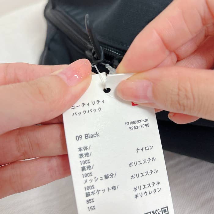 《ライフハック》ハサミを使わずにタグを取る方法。バックパックのタグを指でちぎって取り外している様子。