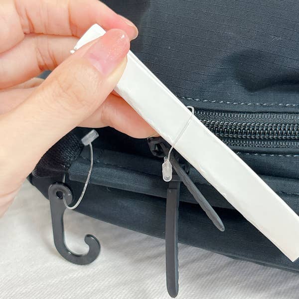 《ライフハック》ハサミを使わずにタグを取る方法。取り外したタグを丸めて、ループにさしこんでいる様子。